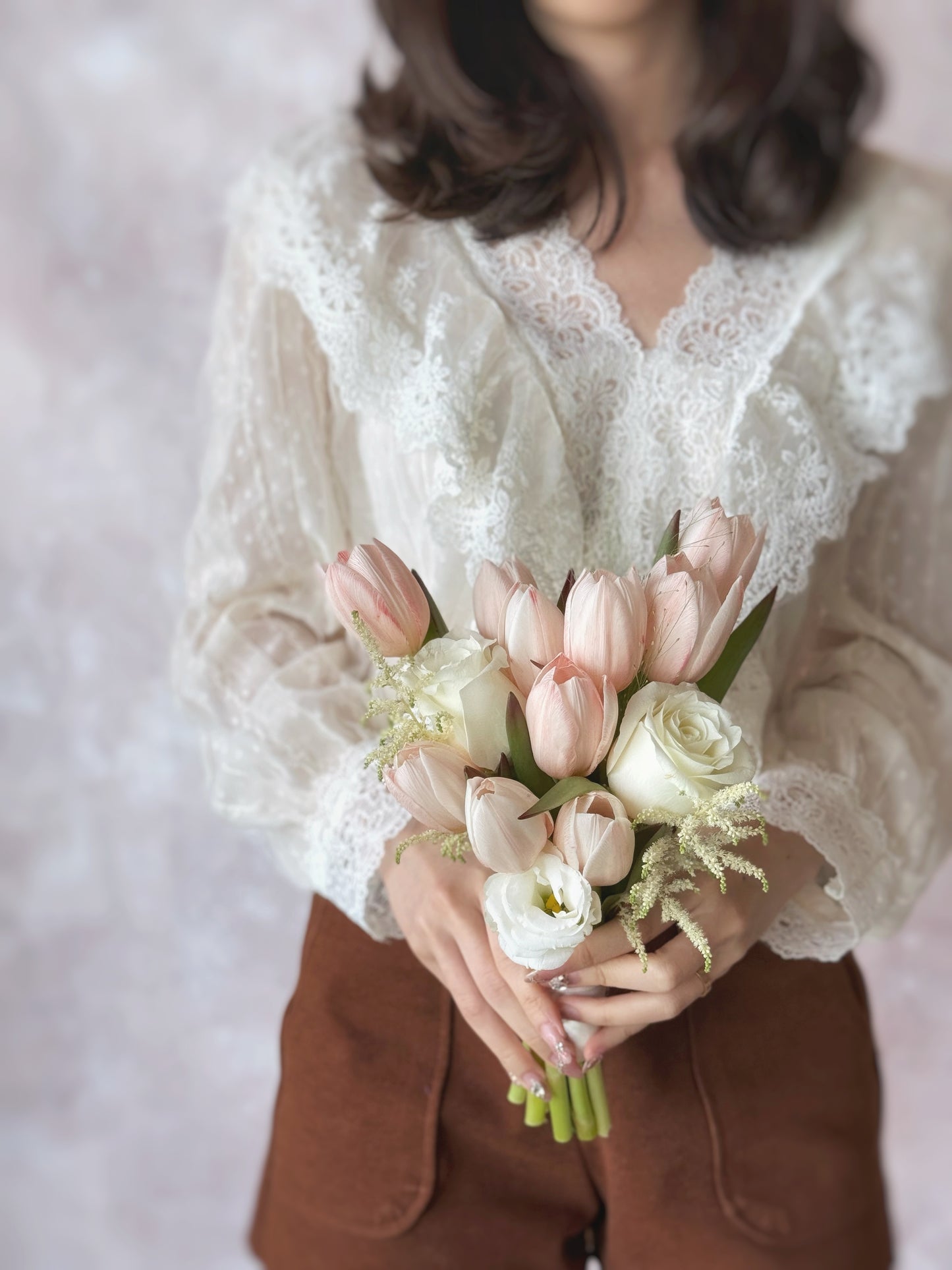 A bride holding the bouquet, its peachy tulips and white blooms complementing her elegant bridal look.
新娘手持捧花,蜜桃色郁金香与白色花朵完美搭配,衬托优雅新娘造型。