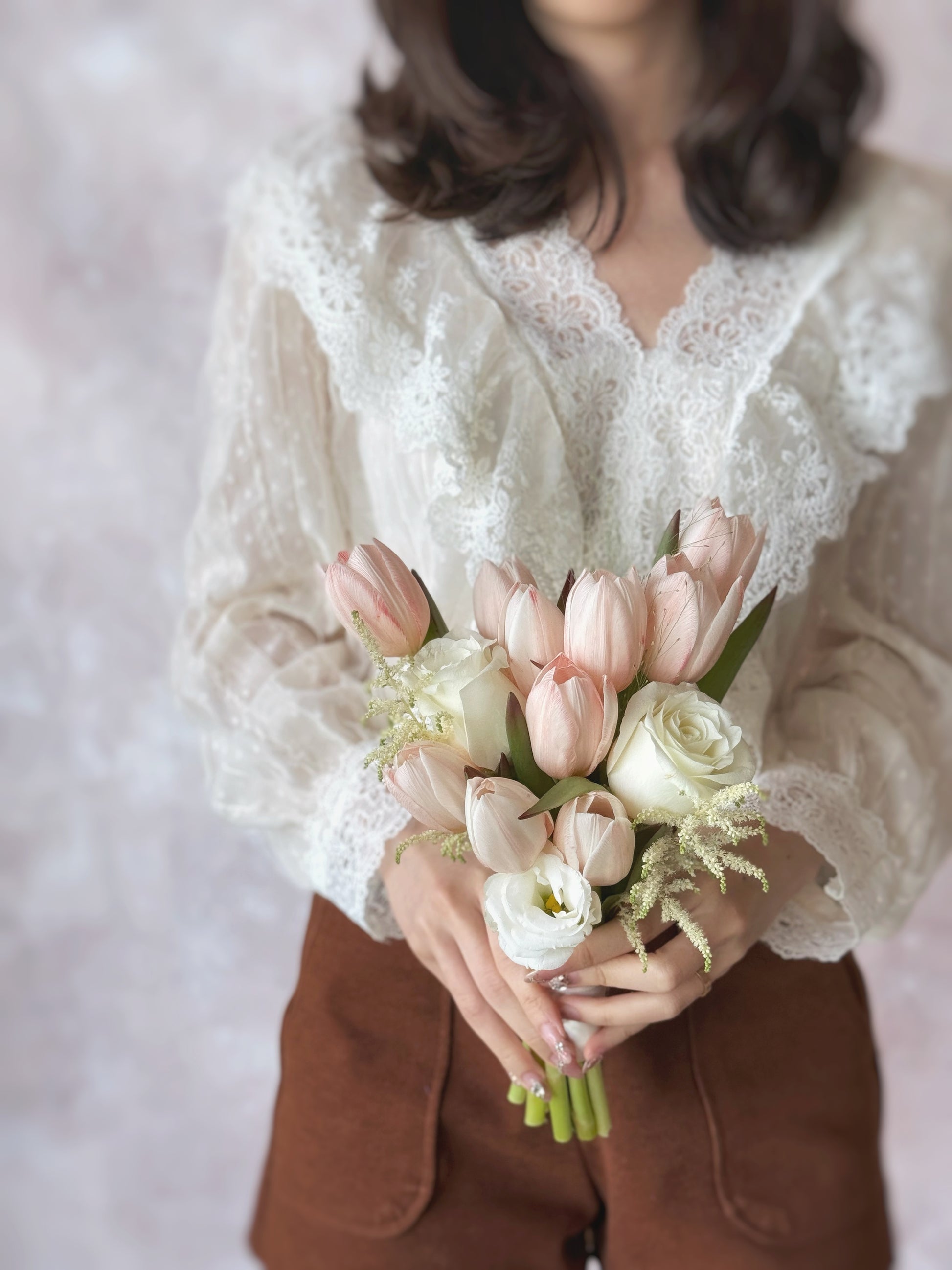 A bride holding the bouquet, its peachy tulips and white blooms complementing her elegant bridal look.
新娘手持捧花,蜜桃色郁金香与白色花朵完美搭配,衬托优雅新娘造型。
