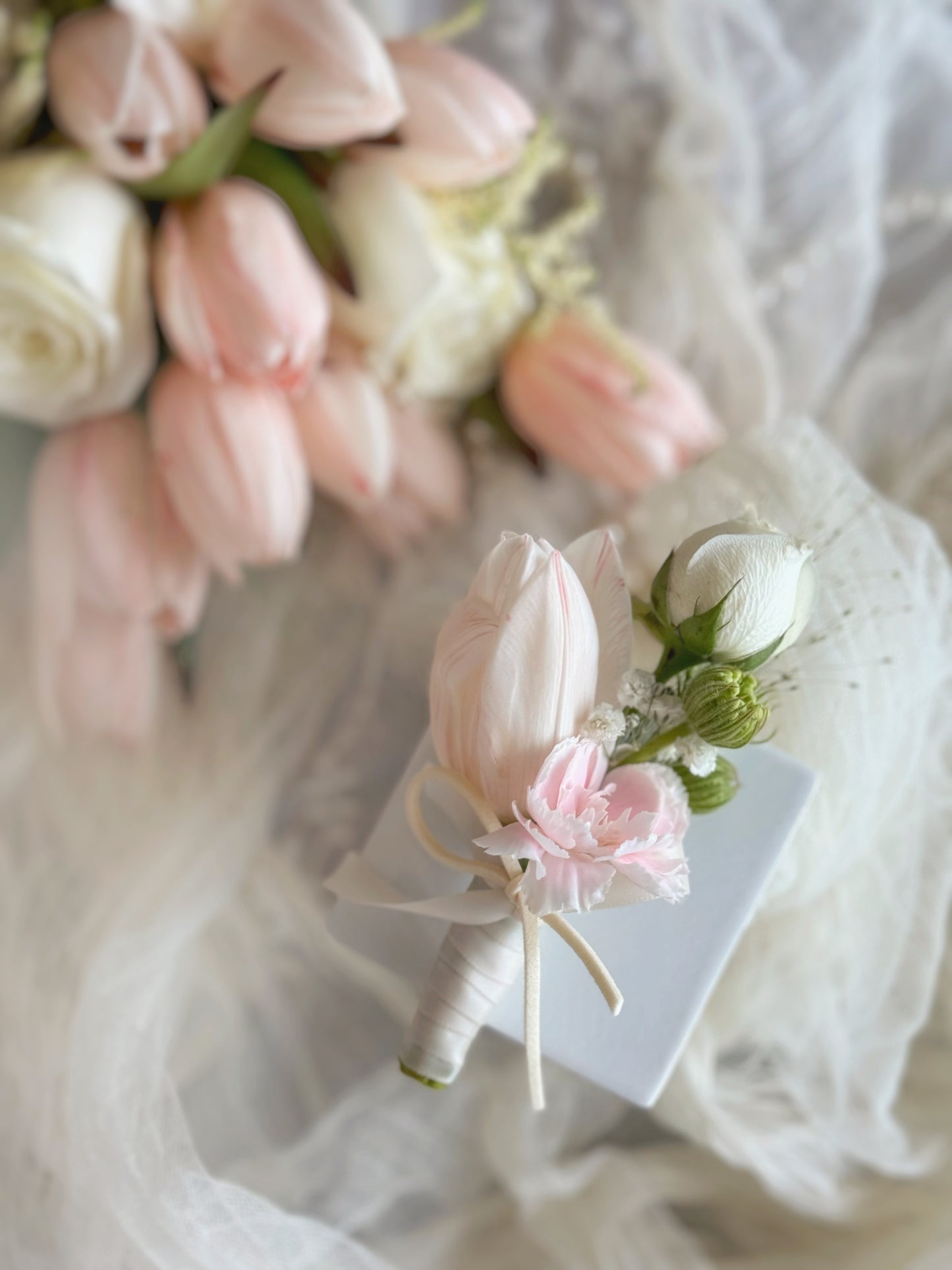 close up view of peachy tulip corsage, pair with pastel pink spray carnation and spray rose