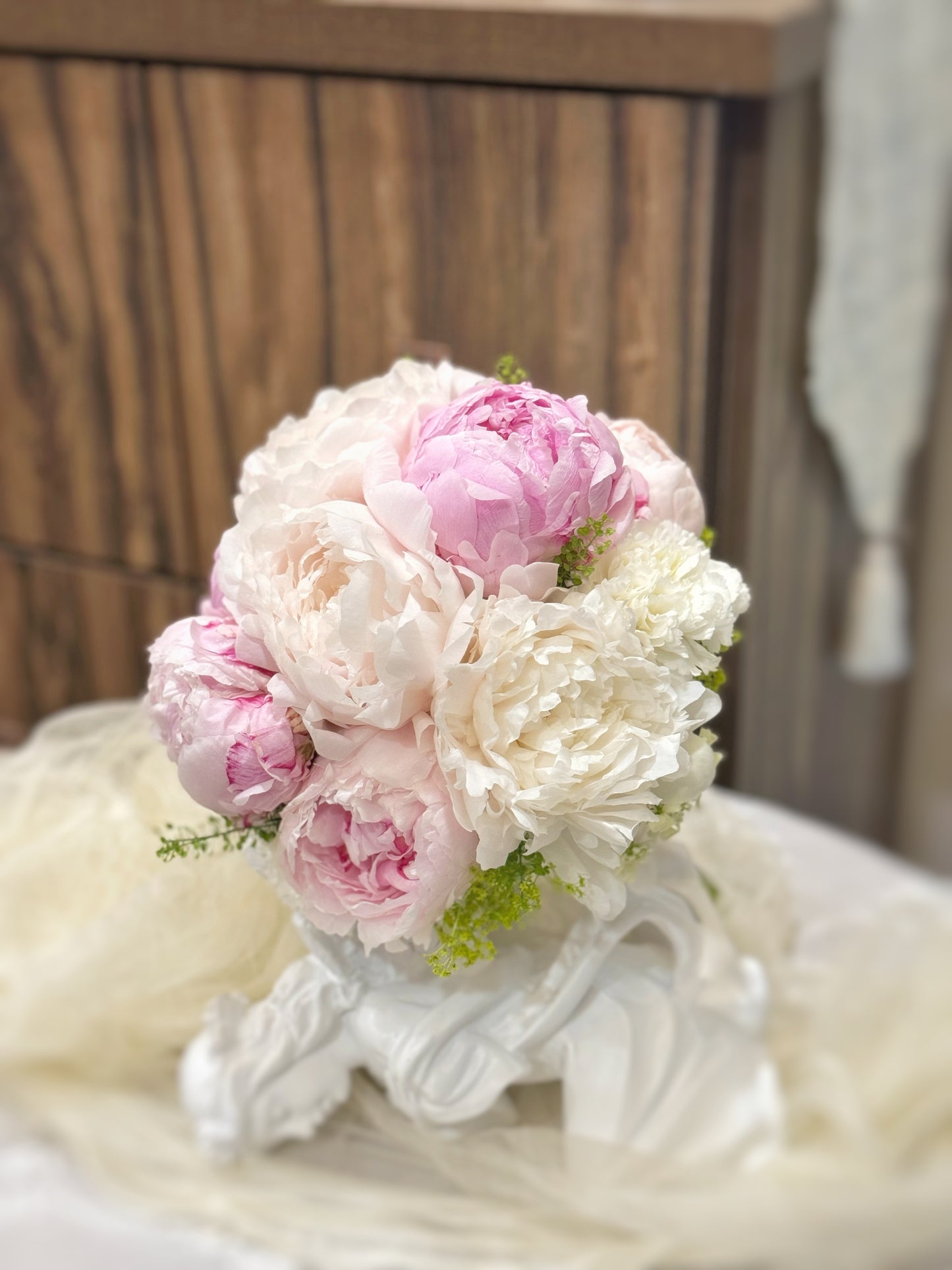 Sarah garden peony fresh flowers round shaped_bridal_bouquet_close view, a luxurious bridal bouquet of pink and white peonies elegantly arranged on a table, showcasing its lush and romantic design
典雅的粉色与白色牡丹花束,营造梦幻般的新娘造型