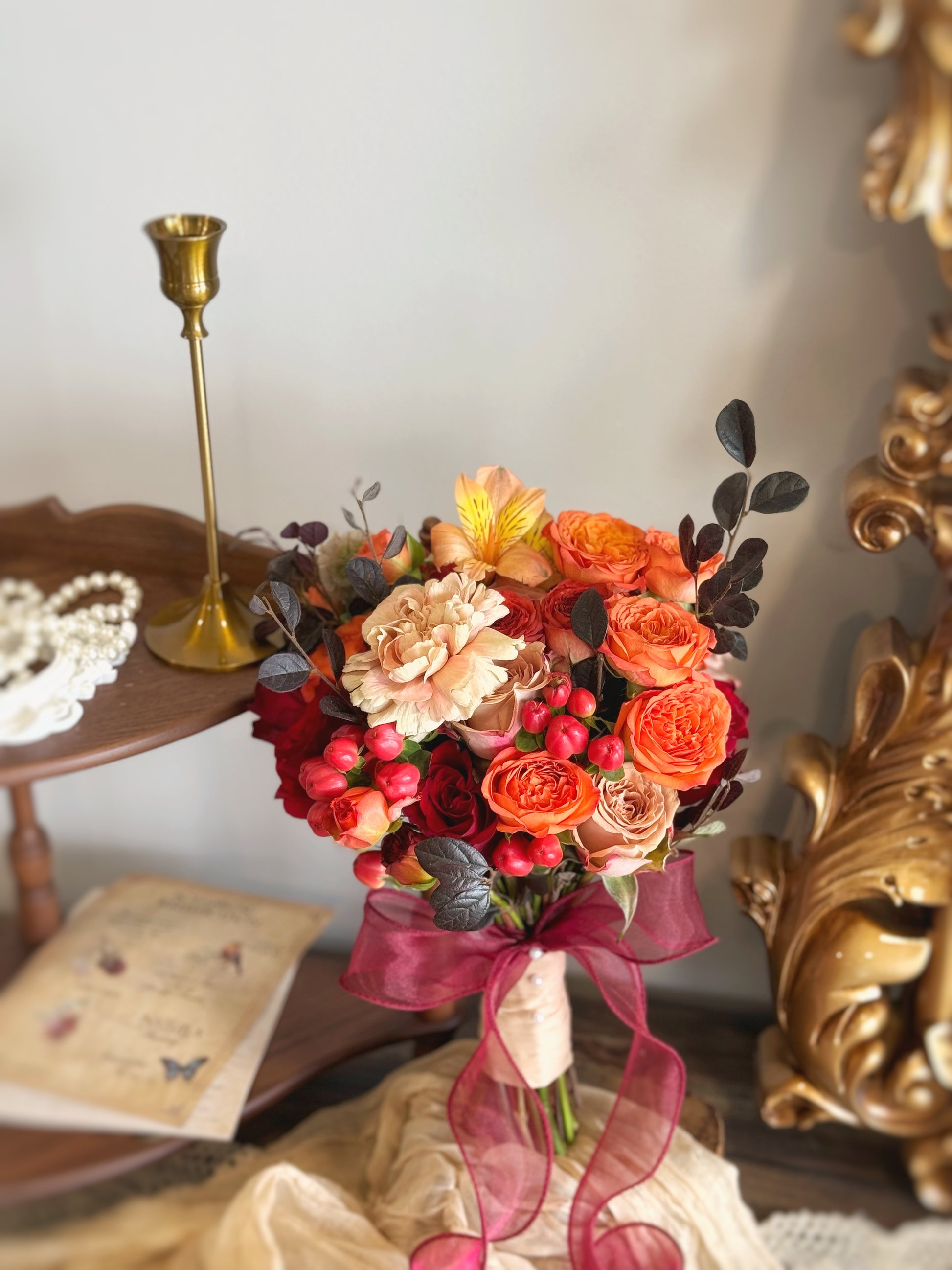 Intricate floral details of a sunset-inspired bridal bouquet, capturing the fiery elegance of red and orange roses
以温暖日落色调打造的圆形鲜花捧花,适合活力四射、充满热情的婚礼风格