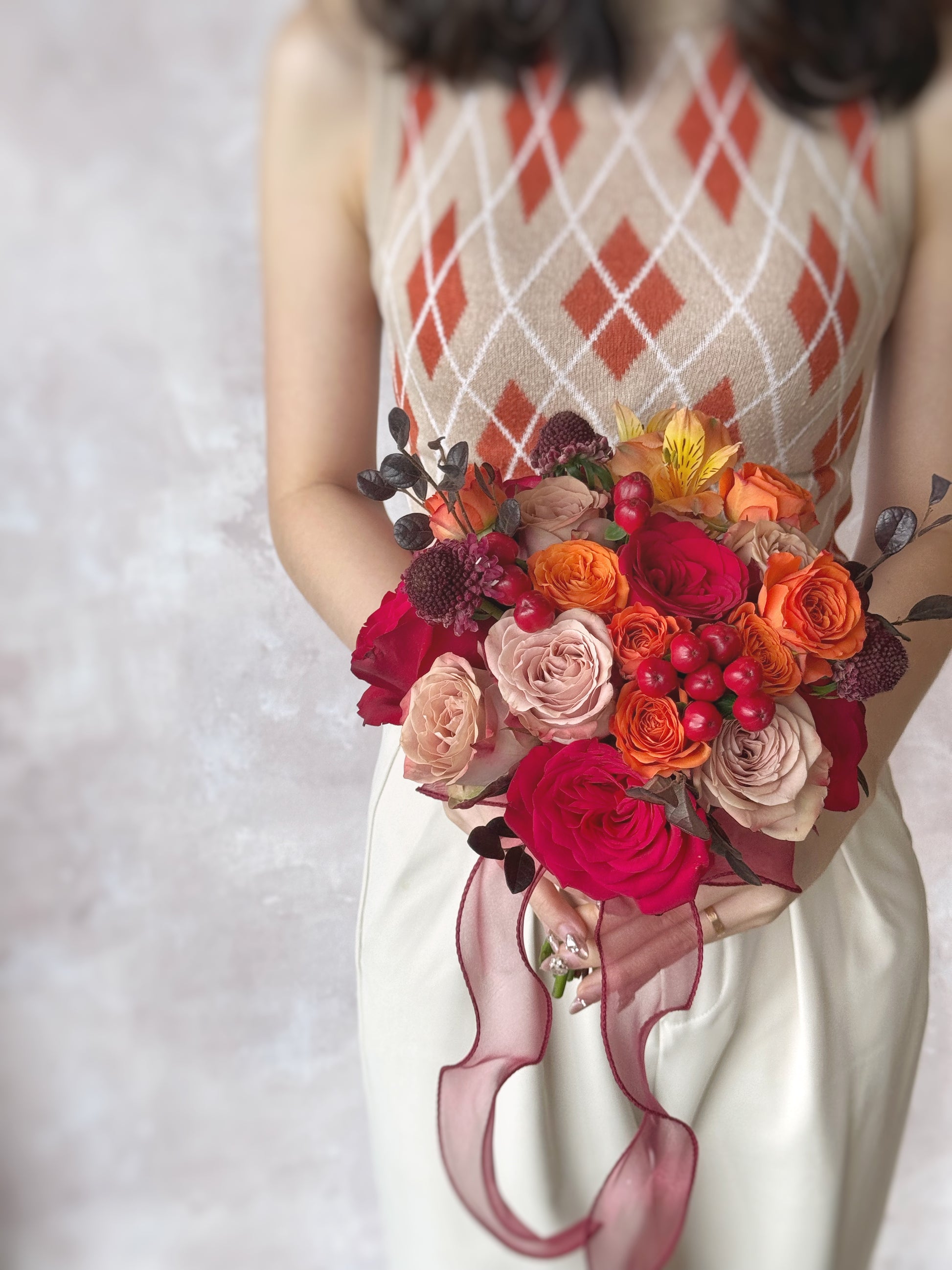 Model holding a bright and bold round bouquet of fresh orange and red roses, inspired by the beauty of a sunset
充满活力的红橙色调捧花,与欢乐明亮的婚礼氛围相得益彰; 鲜艳花瓣的细节特写,展现火热日落捧花的层次与立体感