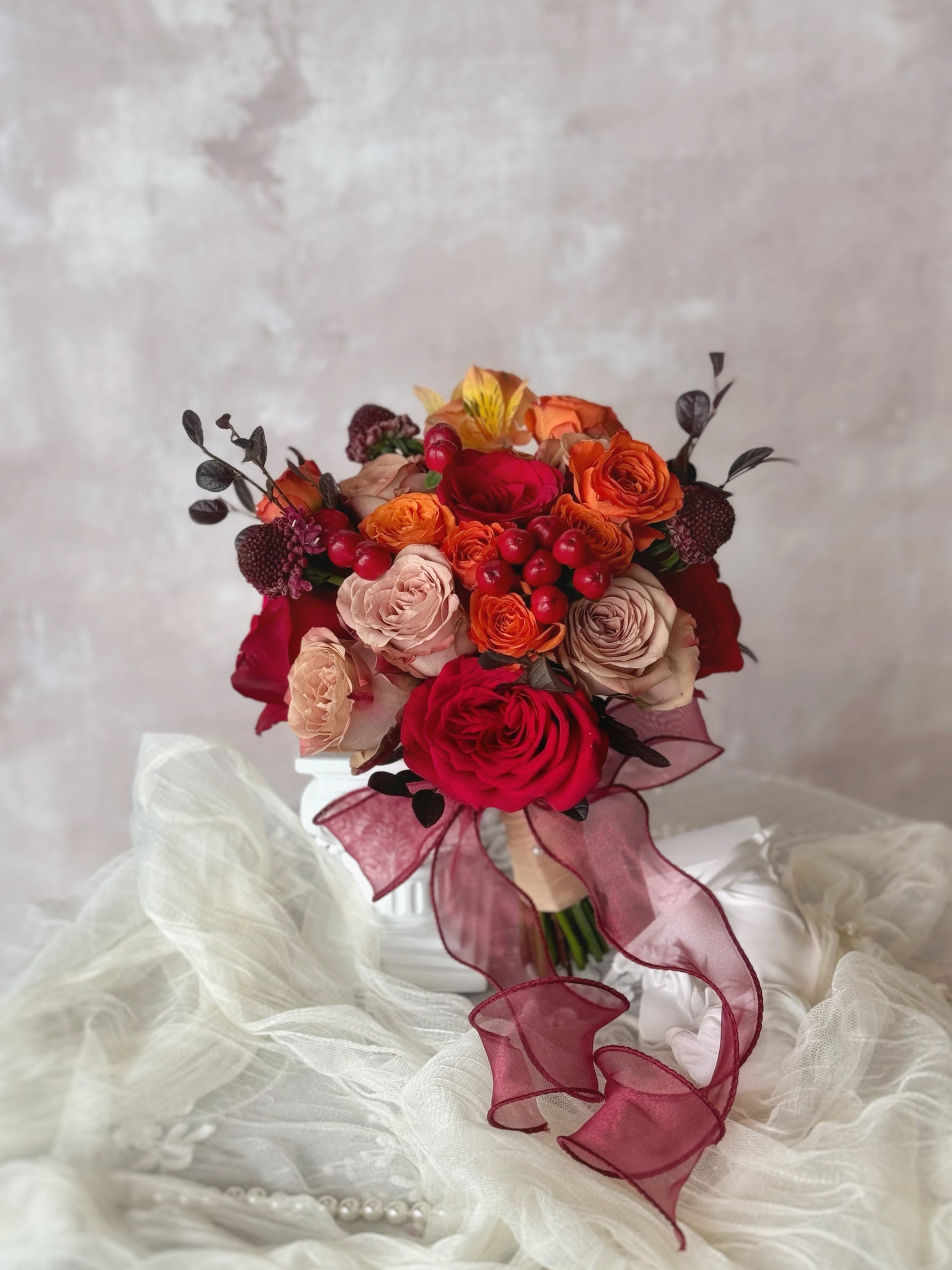 Sunset-hued bridal bouquet resting on a table, showcasing a perfect blend of warm red and orange roses
以夕阳色调为灵感的新娘捧花,融合红色与橙色,呈现温暖而明亮的氛围