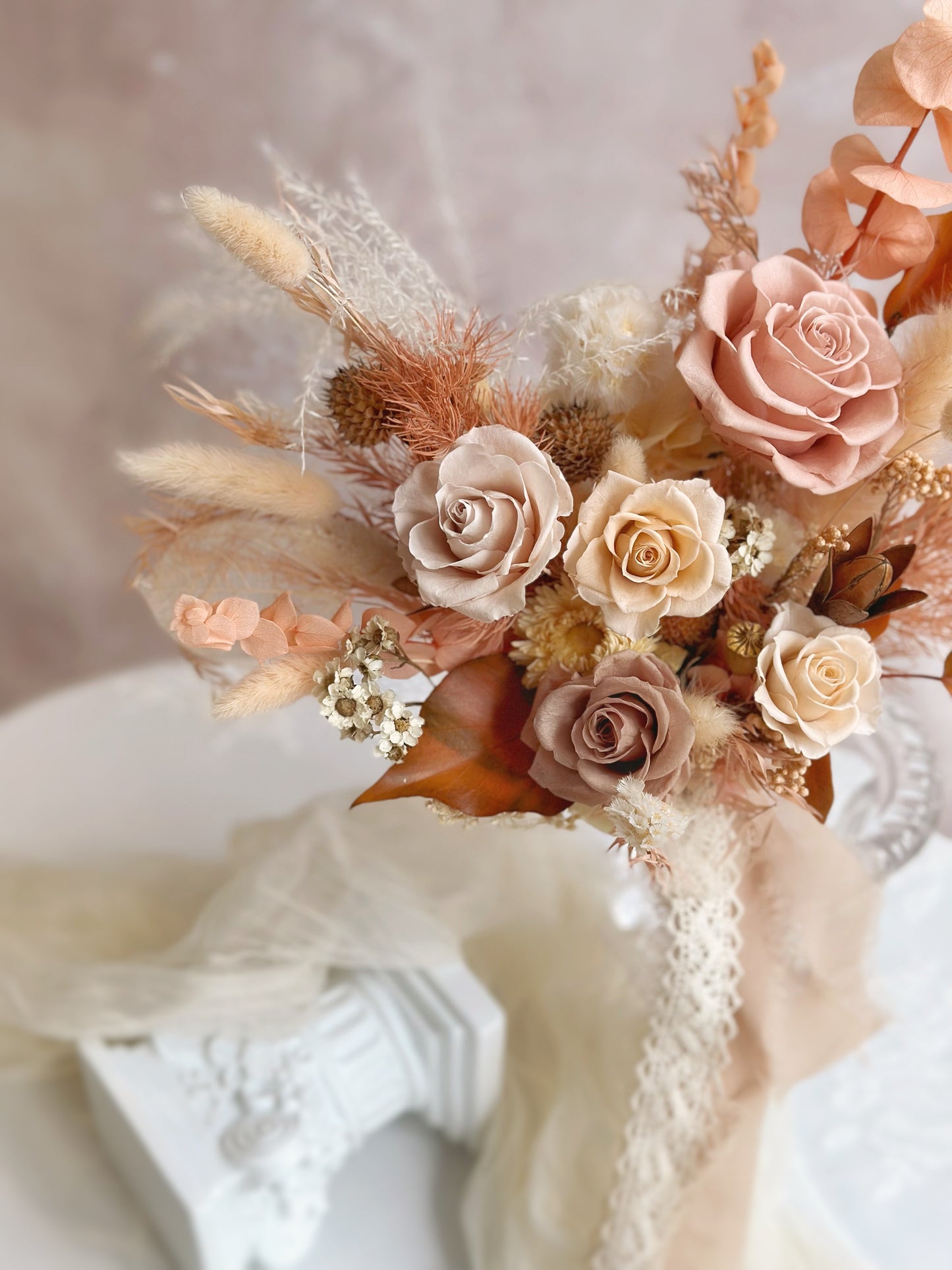 A close-up of the bouquet, showcasing the intricate details of preserved roses and delicate earthy-toned florals.
捧花特写镜头,细腻呈现永生玫瑰与大地色系花材的精致细节。