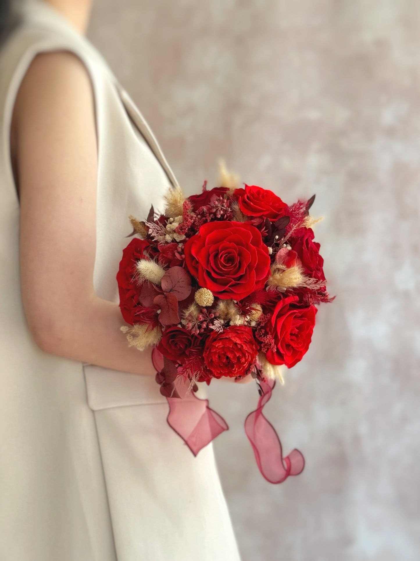 Front view of a round preserved bridal bouquet with maroon, crimson, cream, and warm brown roses — a timeless arrangement blending tradition and elegance.
正面展示圆形永生花新娘捧花,酒红、深红、奶油色与暖棕玫瑰交织,展现优雅与传统的完美融合。