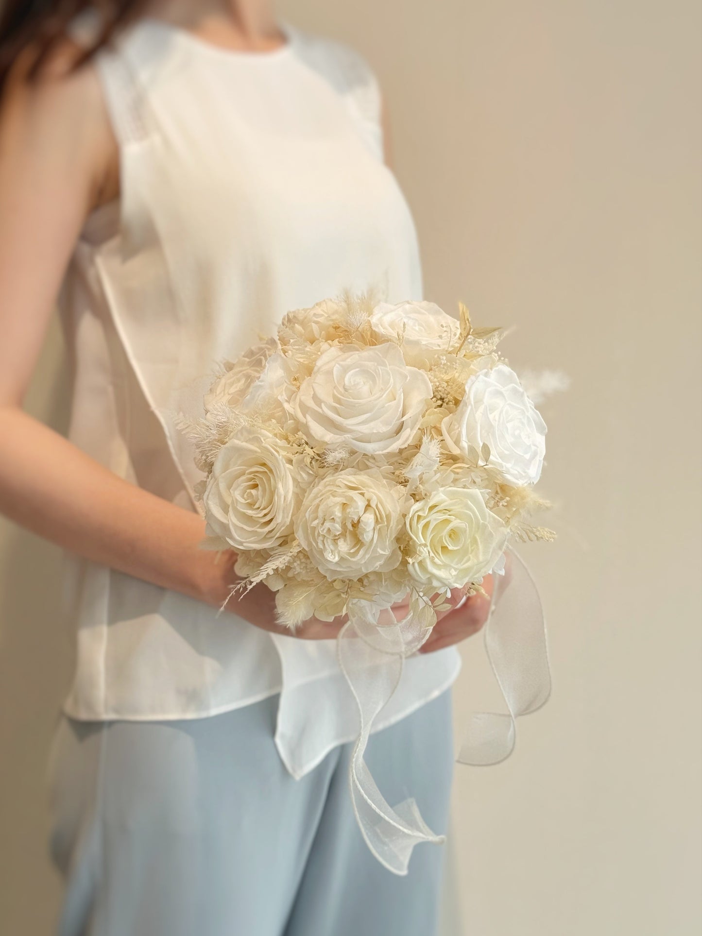 A side profile of the bouquet, highlighting its rounded shape and the soft cascading textures of preserved blooms.
捧花的侧面视角,展现其圆润造型与永生花材的柔和层次感。