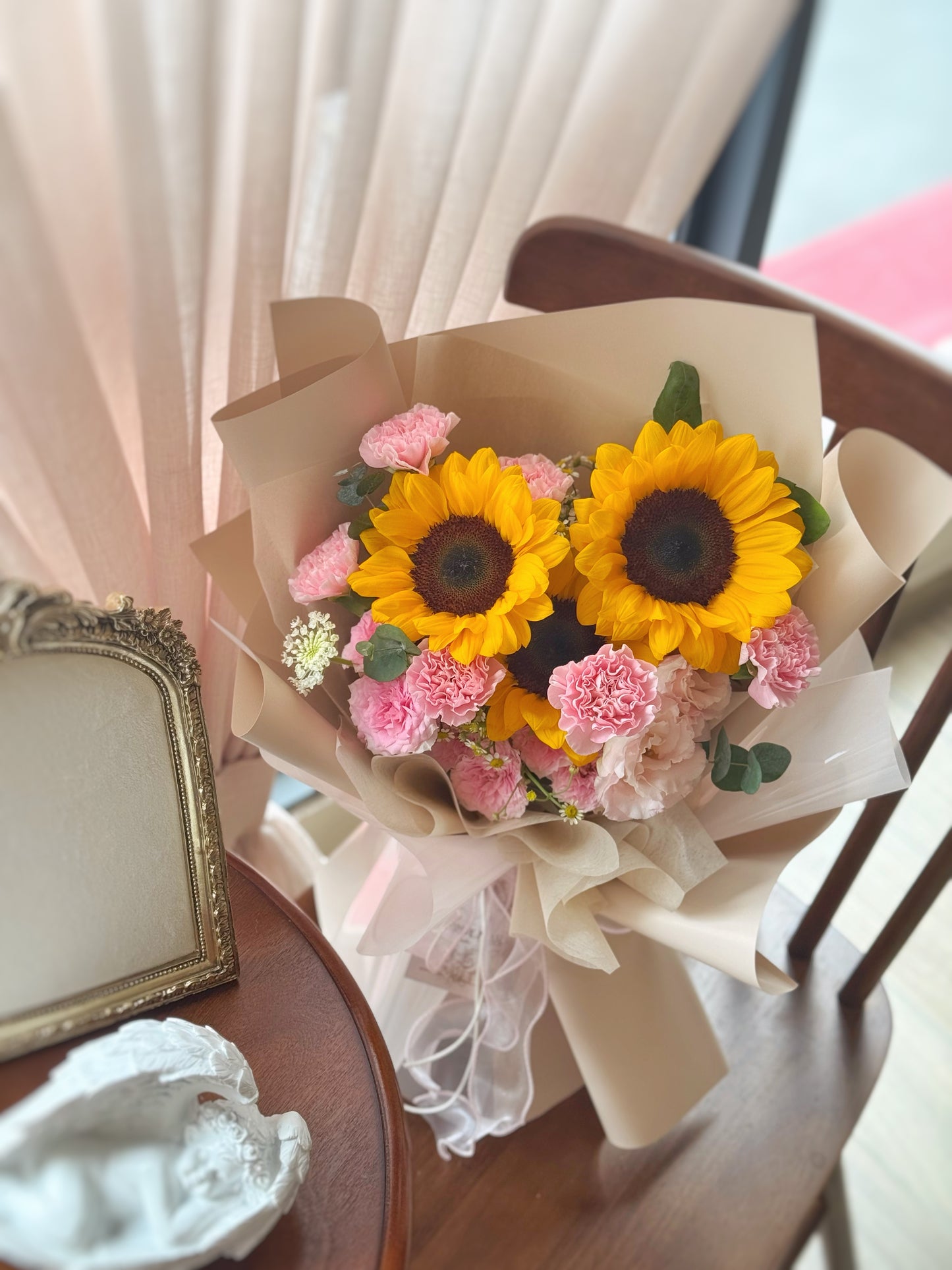 Sunflower and carnation bouquet laid on a table surface, emphasizing its fresh garden feel and rustic charm.
向日葵和粉色康乃馨花束摆放于木椅子上,散发自然花园氛围与朴实温馨的风格。