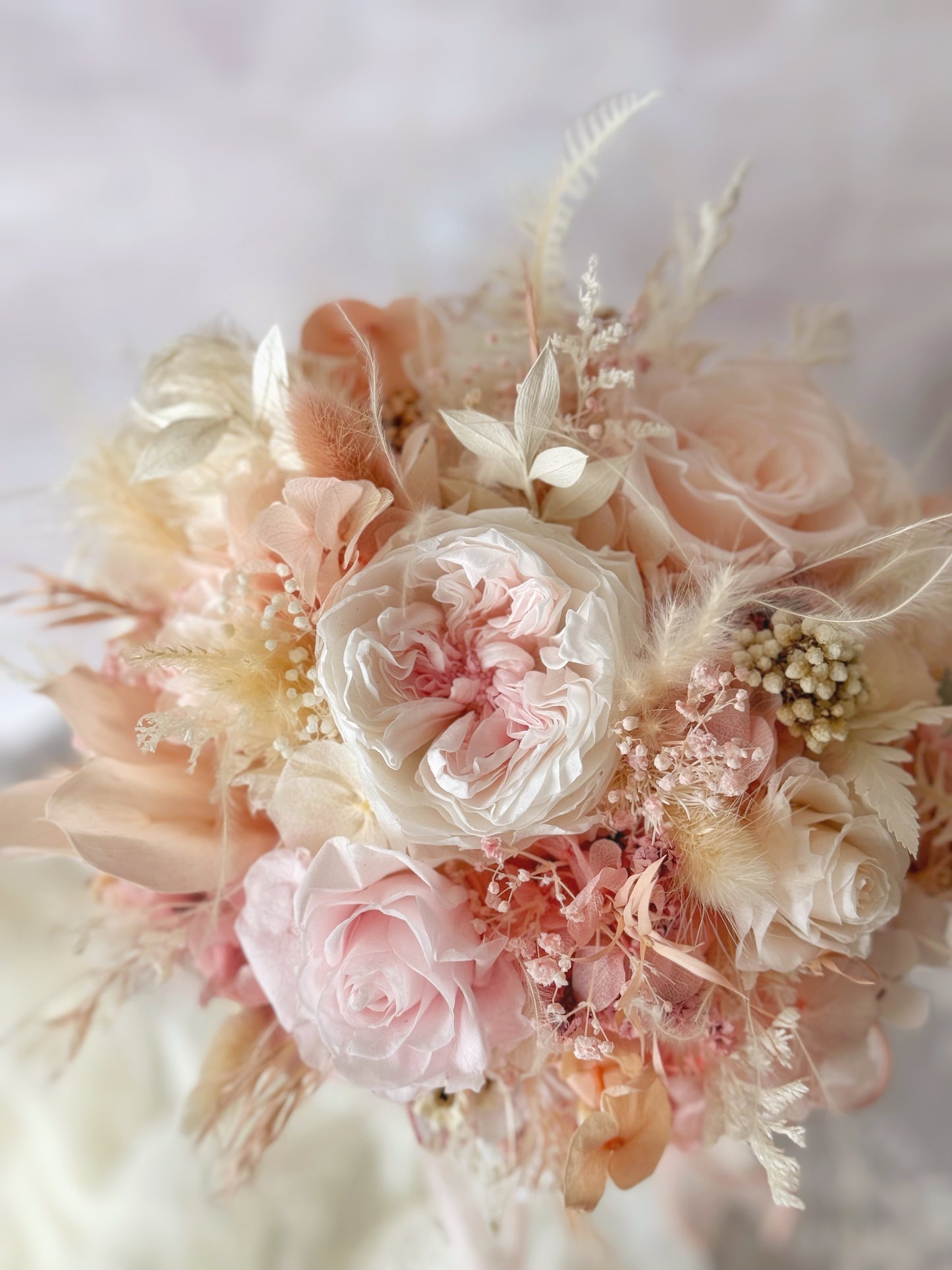 Tea rose preserved flowers round shaped bridal bouquet close up view. The blend of pinkish-peachy tones creates a warm, romantic aesthetic perfect for brides who love soft colors.
粉橘色调的组合营造出温暖浪漫的氛围,适合喜欢柔和色彩的新娘。