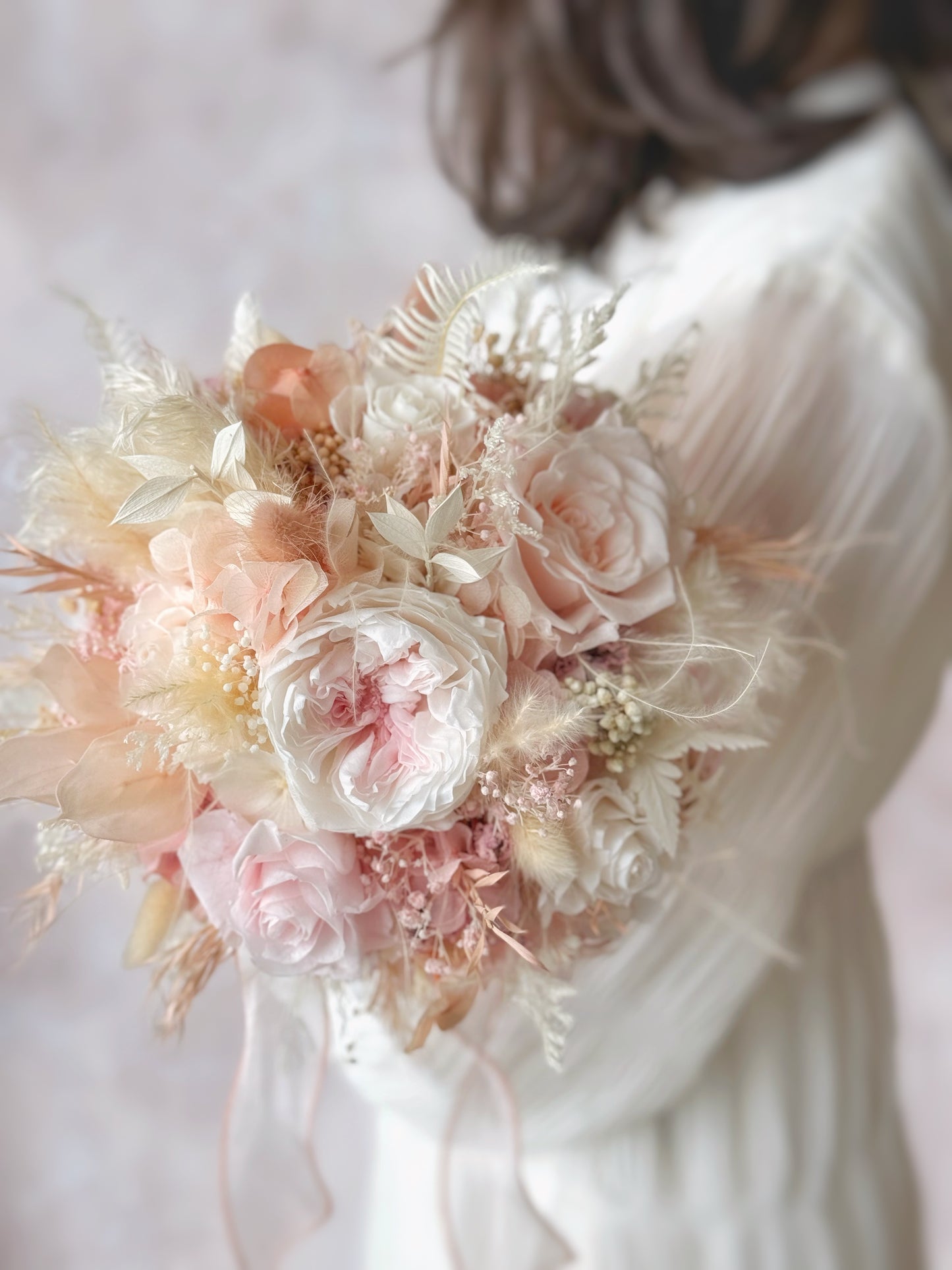 Tea rose preserved flowers round shaped bridal bouquet in front of model. A detailed close-up of the preserved floral textures, highlighting the soft petals and intricate details of each bloom.
特写镜头捕捉永生花的细腻质感,展现每一朵花瓣的柔软与精致细节。