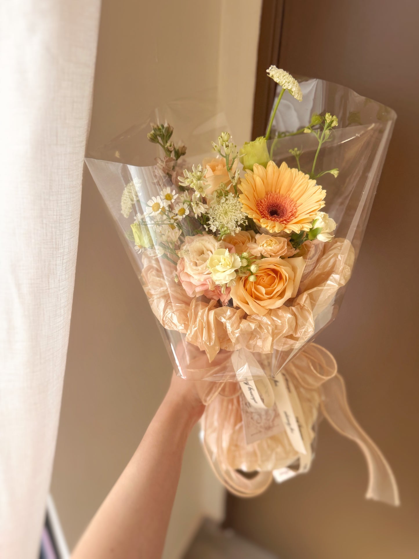 Bouquet held in hand by a model, showcasing the bouquet’s soft tones and sheer wrapping in a minimalist, romantic look.
模特手持花束,整体色调柔和,透明包裹清新浪漫,呈现简约优雅风格。