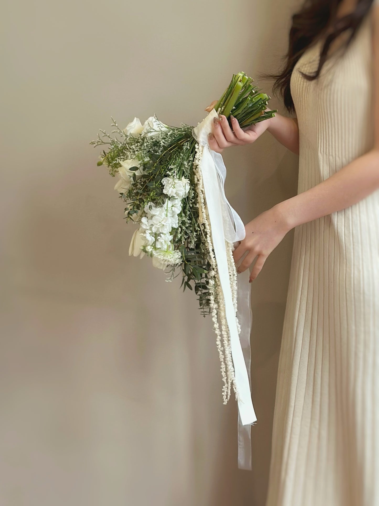 A side profile of the teardrop bridal bouquet, showcasing its elegant cascading effect. The long white tulips gracefully drape downward, complemented by delicate greenery and soft floral accents, creating a natural, free-flowing silhouette. This side angle highlights the bouquet’s depth and dimension, making it a stunning choice for brides who appreciate organic and airy designs.
这款水滴形新娘捧花的侧面角度展示其优雅的垂坠效果。修长的白色郁金香轻盈下垂,搭配精致绿植和柔和花卉点缀,形成自然流畅的轮廓。从侧面观赏,能更好地体现花束的层次感和立体感,是喜爱有机、轻盈花艺设计新娘的理想选择。