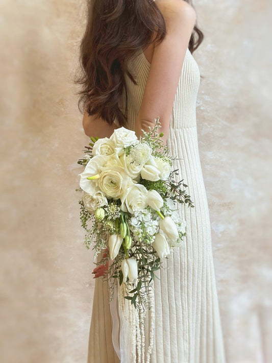 A dreamy garden fairytale bridal bouquet with cascading blooms and foliage, featuring wispy foliage, white tulips, roses, ranunculus, anthurium and caspia flower.
田园风格新娘捧花,结合垂坠白色郁金香与叶材