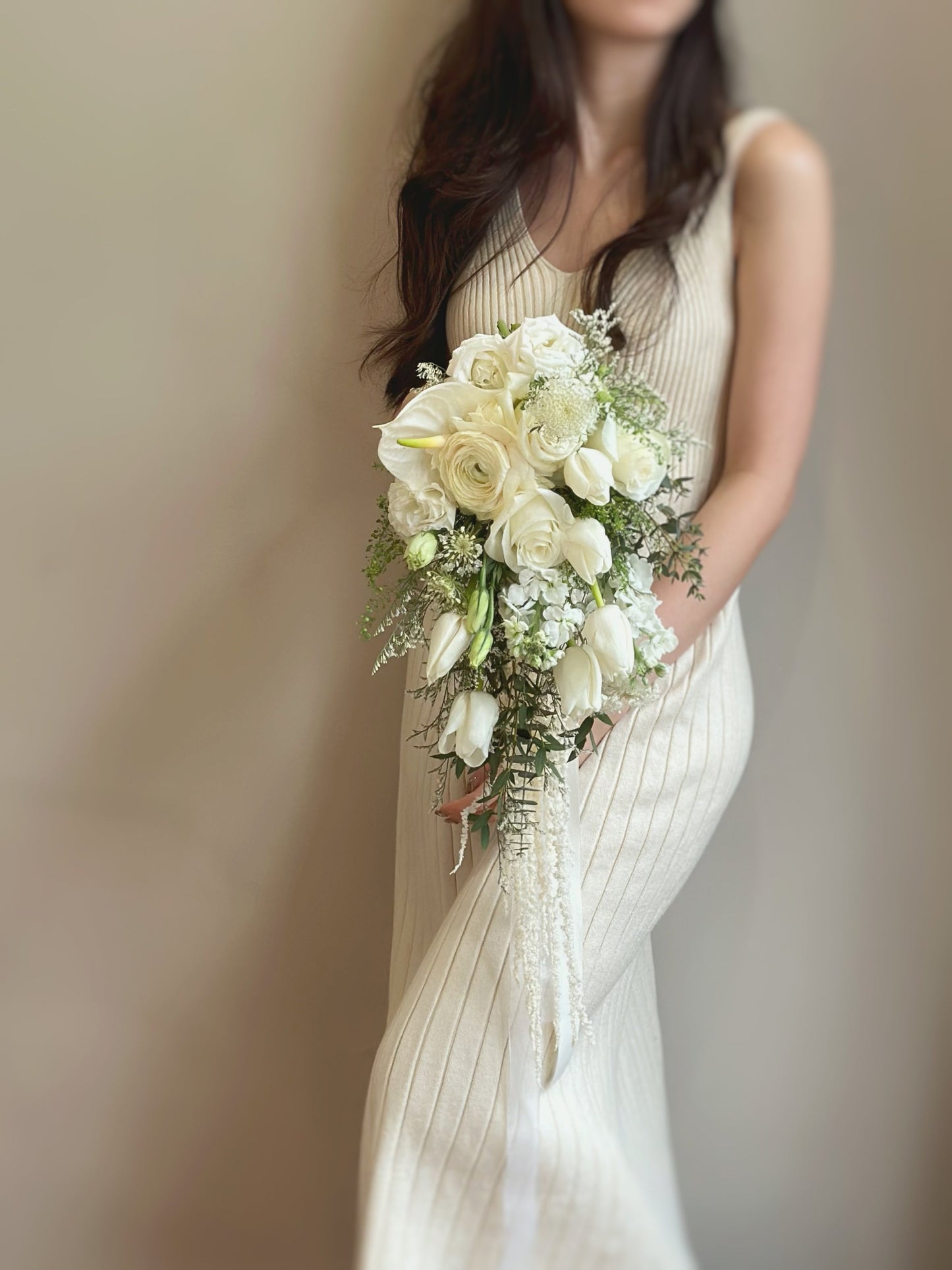 Bride holding a flowing teardrop bouquet with white tulips, roses,anthurium, caspia, eustoma, matthiola and soft greens
新娘手持流畅水滴型捧花,点缀白色郁金香与柔和绿叶