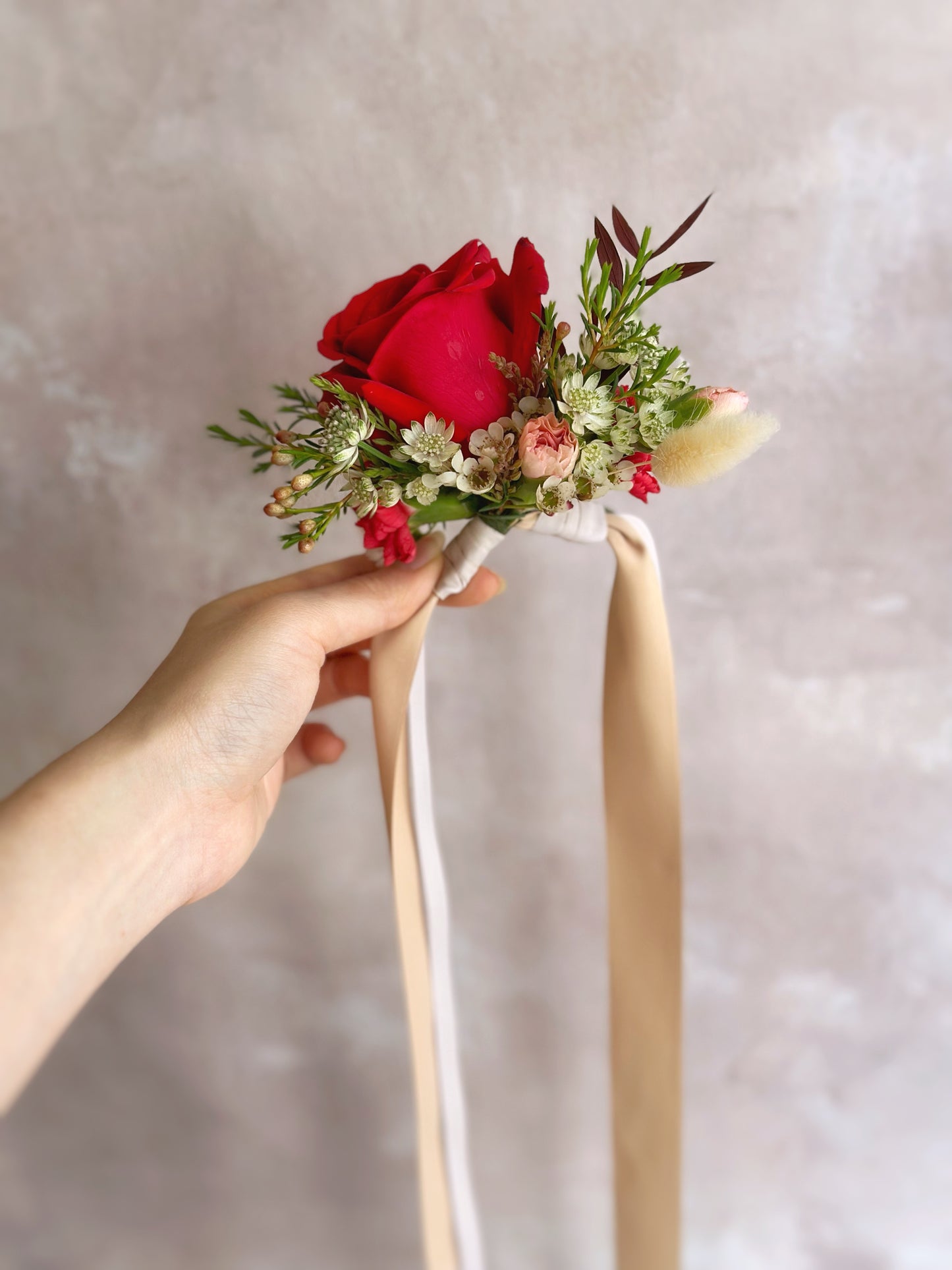 red roses wrist corsage with lush greeneries side view