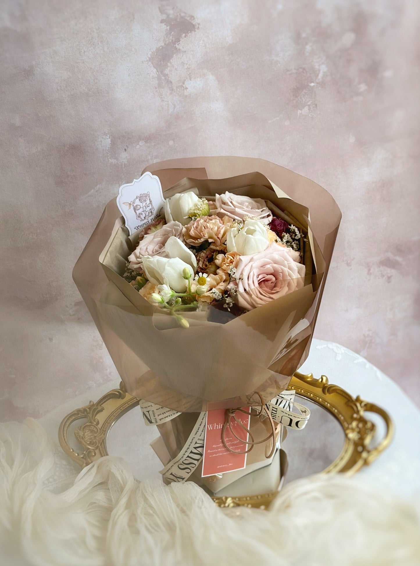 Bouquet laid flat on a table, highlighting its soft coffee-inspired tones and stylishly structured wrap — perfect under natural light.
花束平放在桌面,自然光下展现咖啡色调花材与有型包裹的优雅融合。