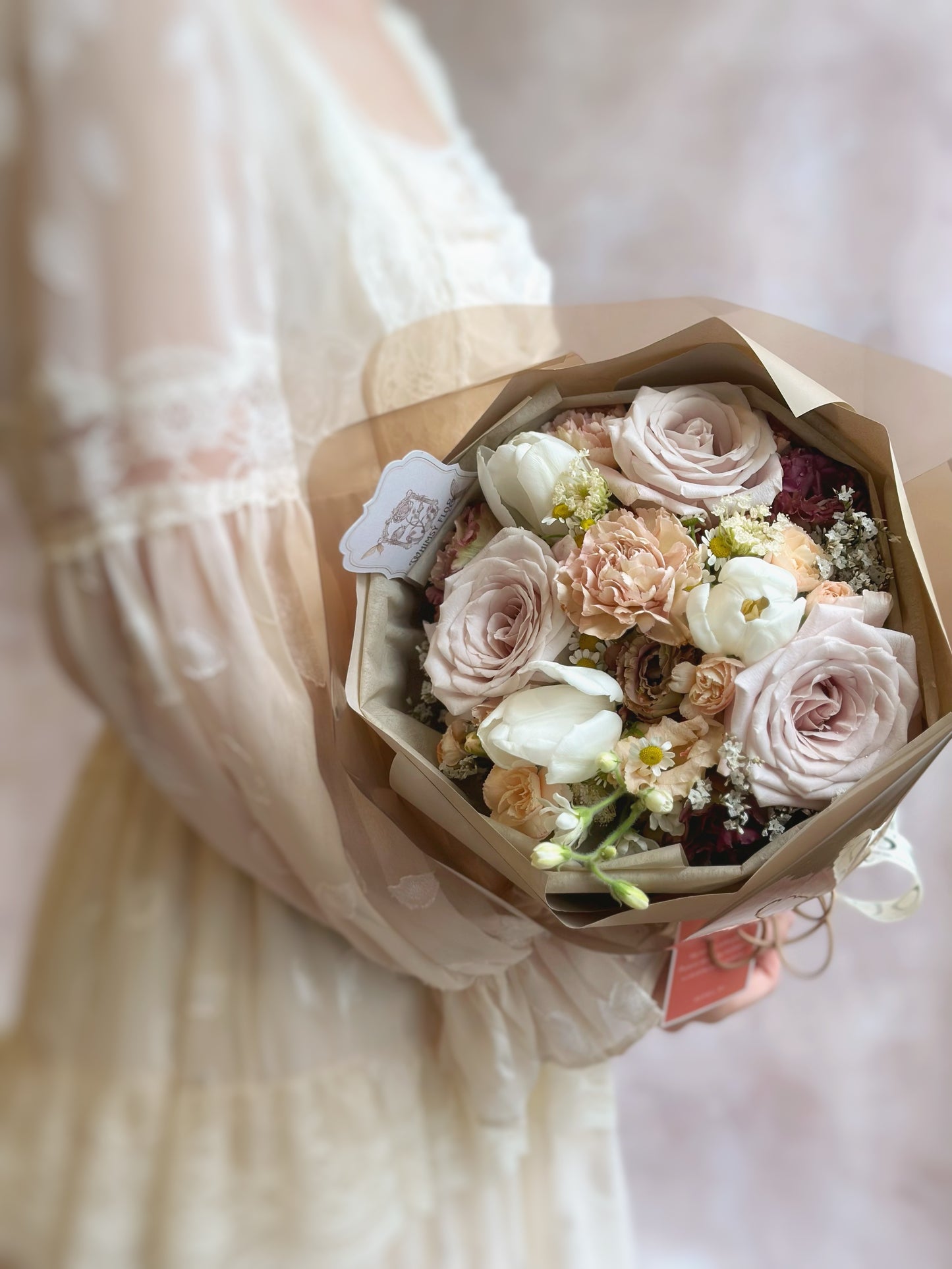 Top-down view of the bouquet with a harmonious mix of muted flowers and rich greenery, arranged in a balanced, circular form.
俯视图展现柔和花材与绿叶的协调搭配,构成平衡的圆形花束结构。