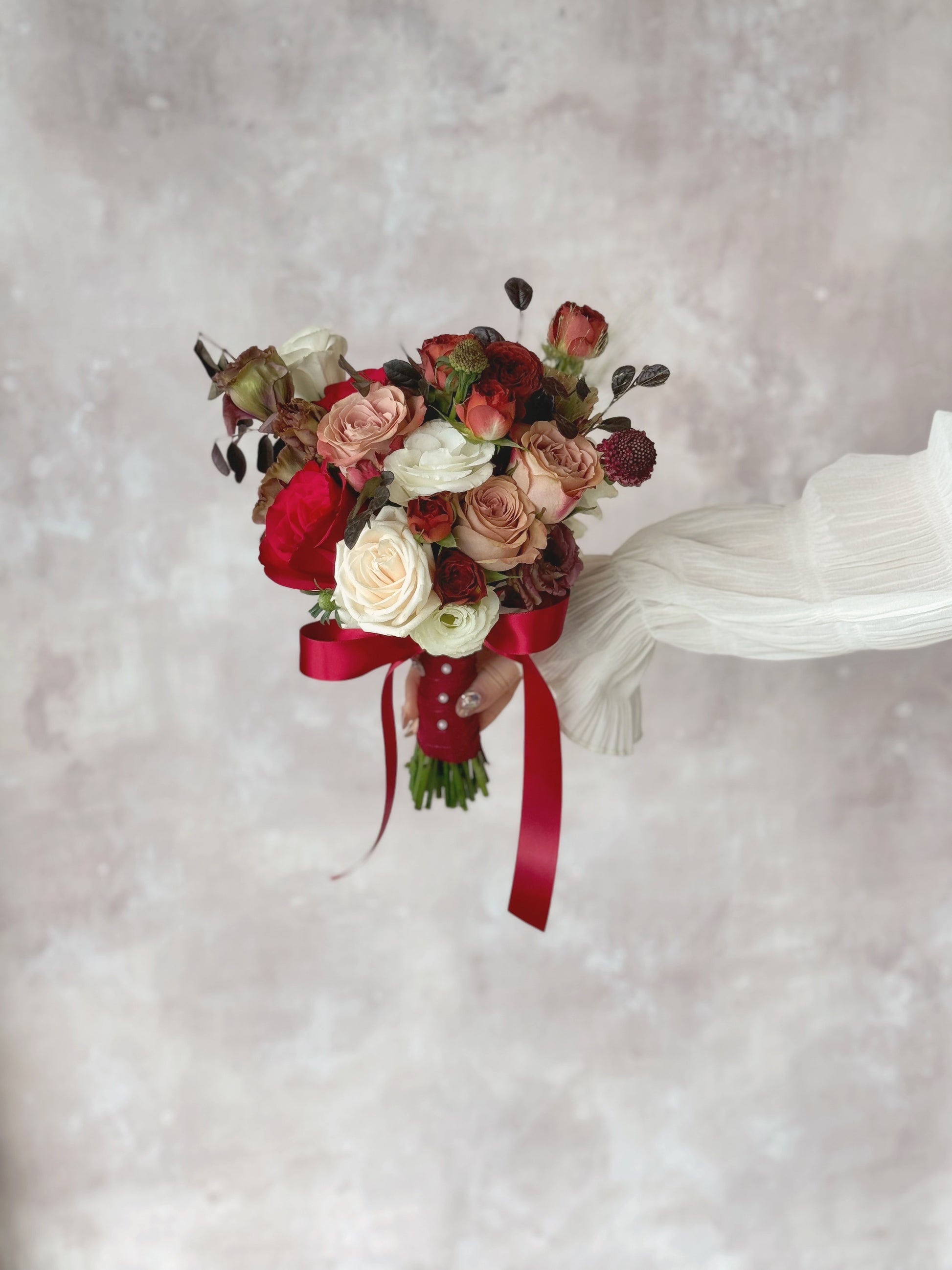 A bride holding a dramatic mauve and maroon bouquet, adding an air of mystery and sophistication to her wedding look
新娘手持深紫红与酒红捧花,为婚礼造型增添神秘感与优雅气质