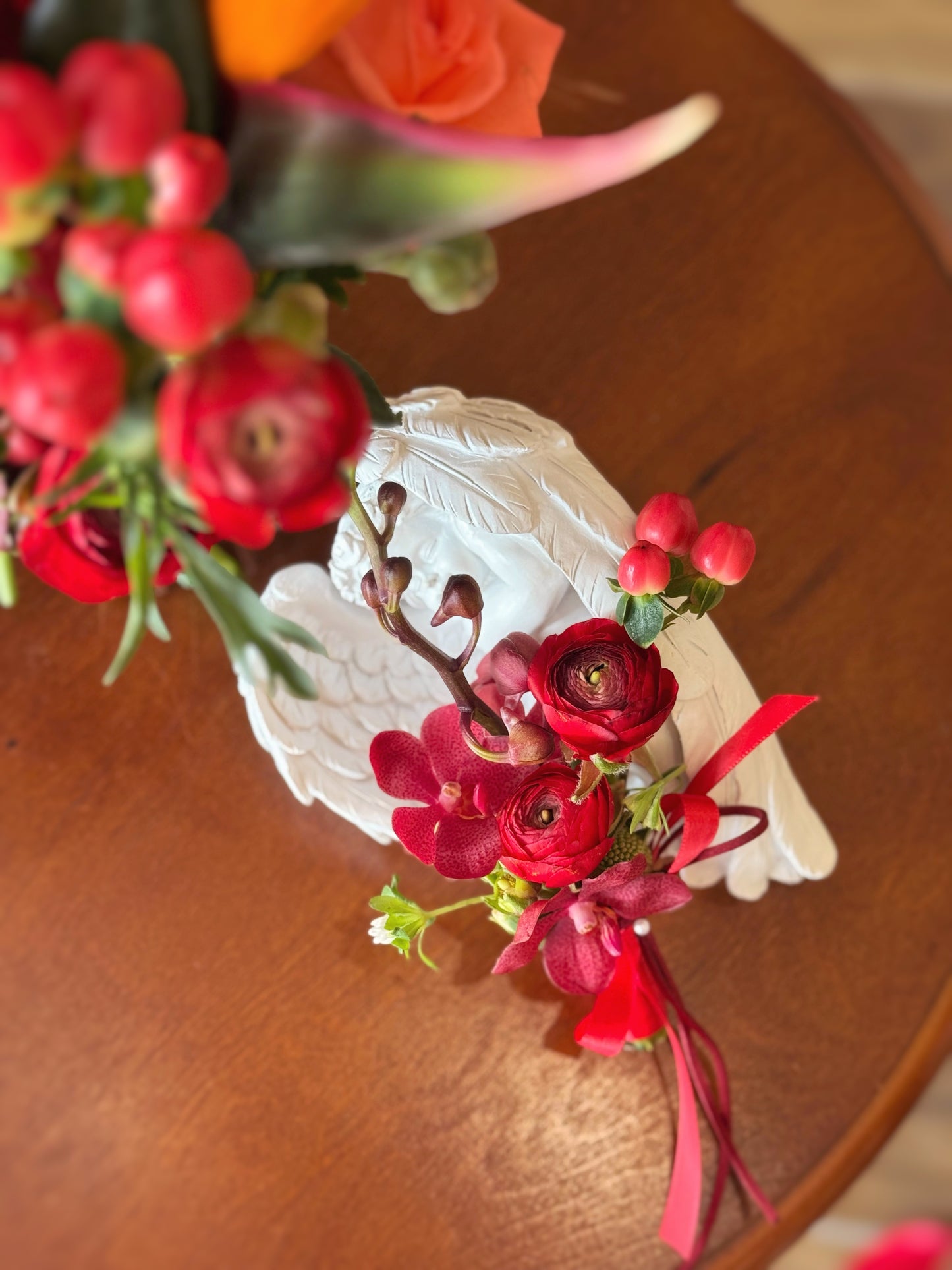 red ranunculus flowers corsage and green stems on a warm brown wooden surface.