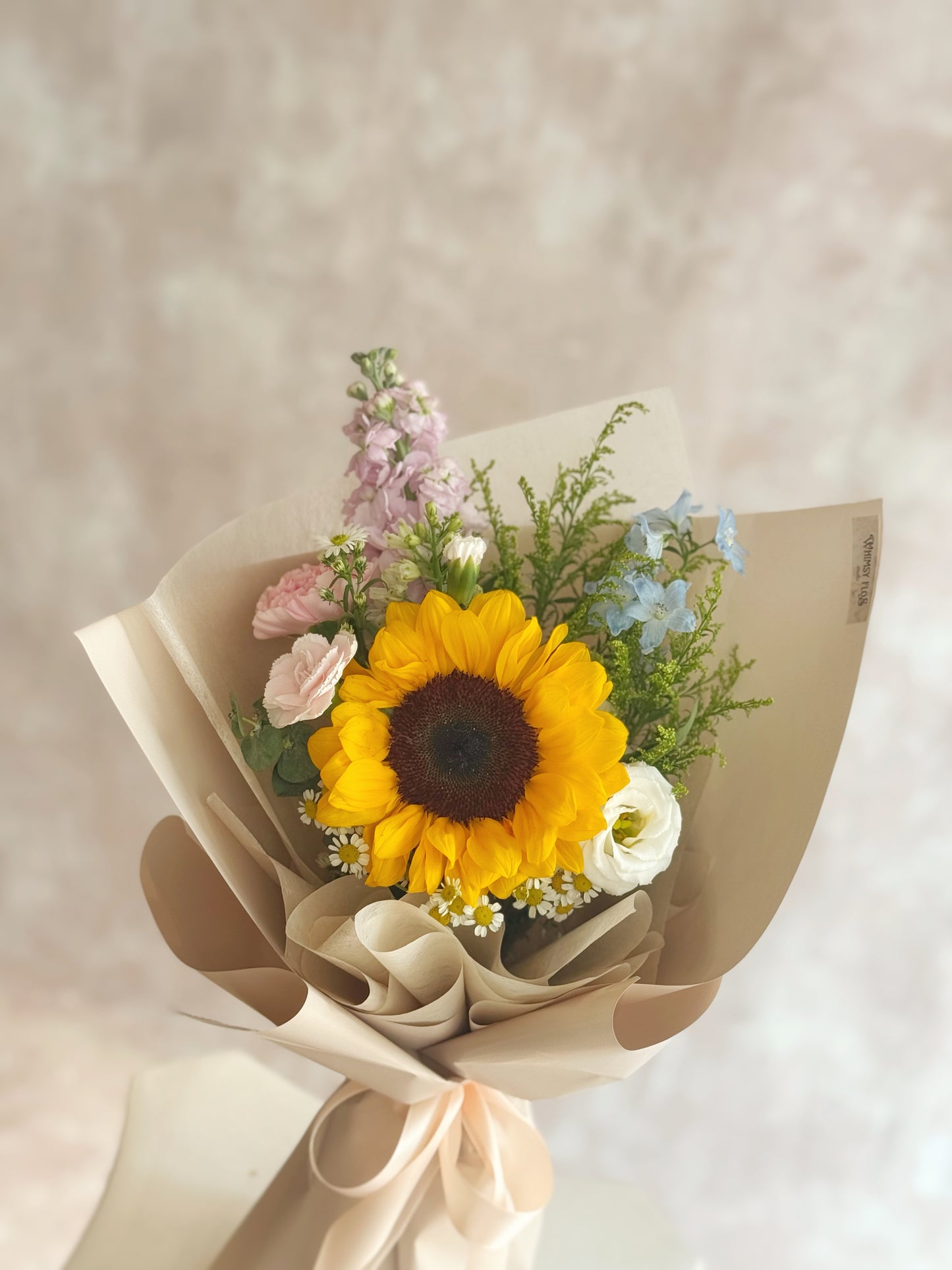 Close-up of the sunflower center, with soft-petaled pastel flowers and daisy accents framing it in gentle textures.
向日葵花心特写,柔和花瓣的粉色系小花与小雏菊相互衬托,细节温柔可爱。