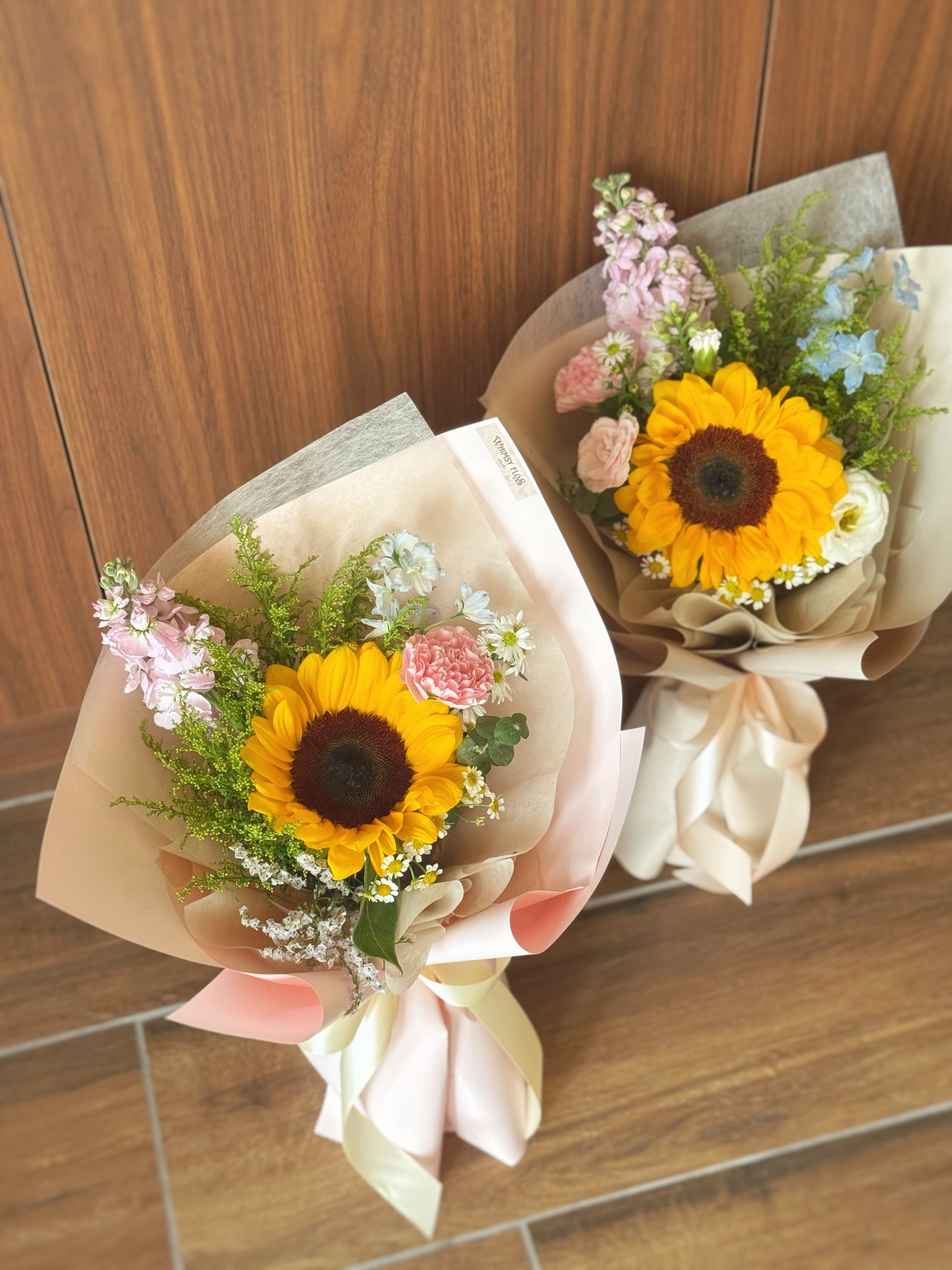 Top-down view showing a compact arrangement of one sunflower and pastel blooms, highlighting its soft, joyful color palette.
俯视图呈现紧凑且协调的花材布局,柔和色系传递出轻松愉快的氛围。