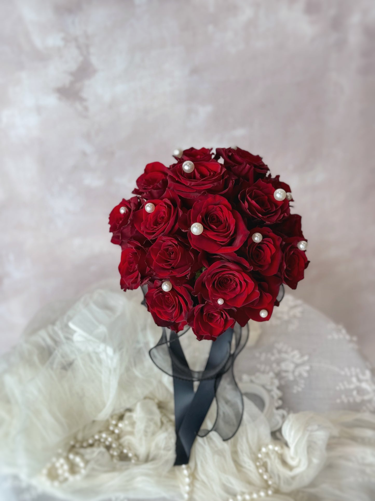 Beatrice fresh flowers round shaped bridal bouquet on the table , featuring pearl embellishments and a bold black ribbon for a sophisticated touch
