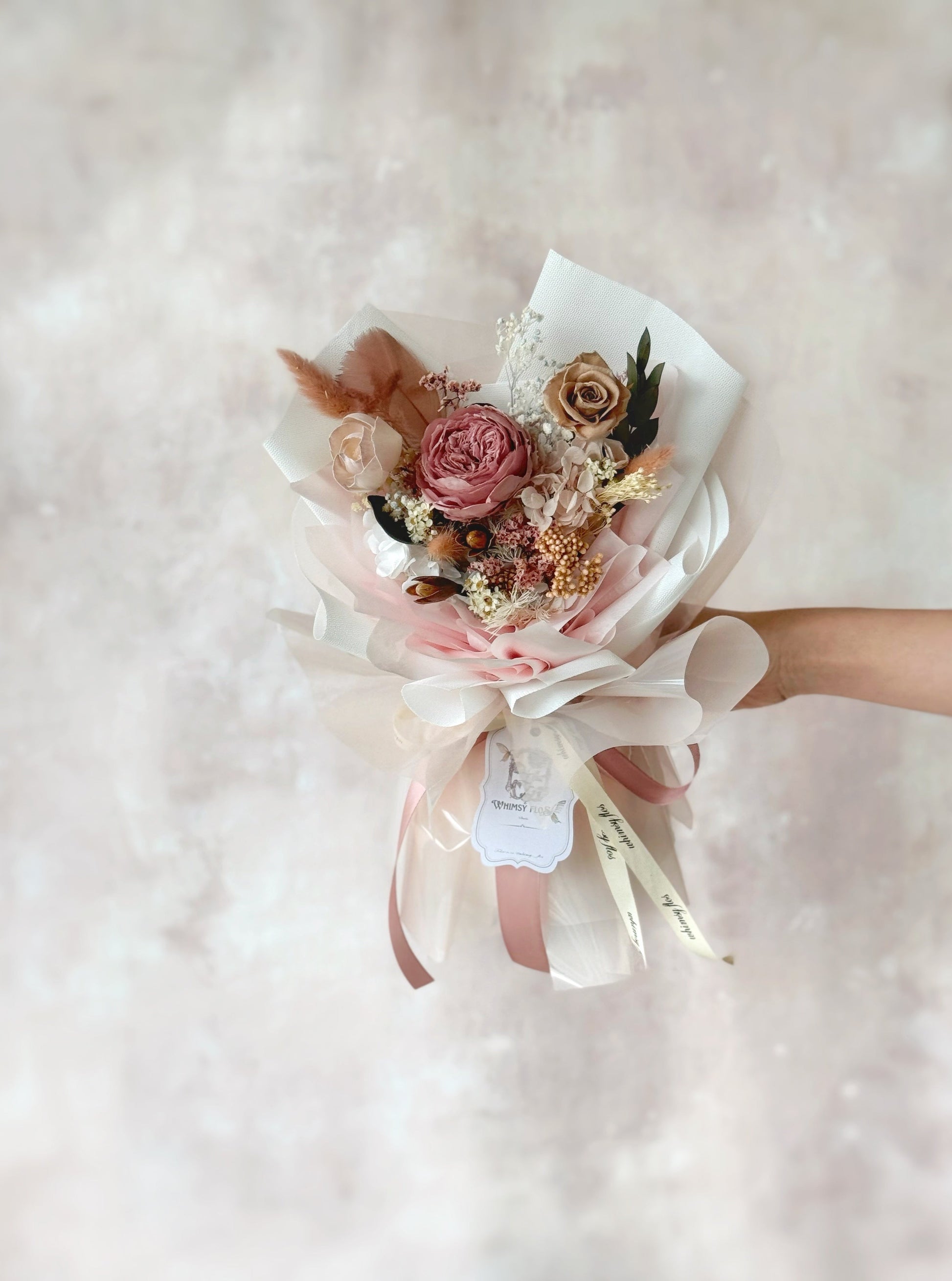 Vintage themed preserved flowers bouquet in dusty pink colour front view handheld