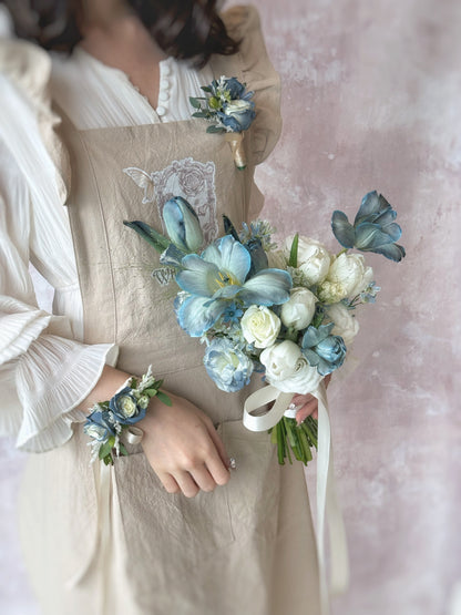 A set of matching bridal bouquet, boutonniere and wrist corsage curated for a dusty blue, white and green wedding color palette
灰蓝色新娘捧花与新郎胸花完美搭配，打造和谐婚礼造型

