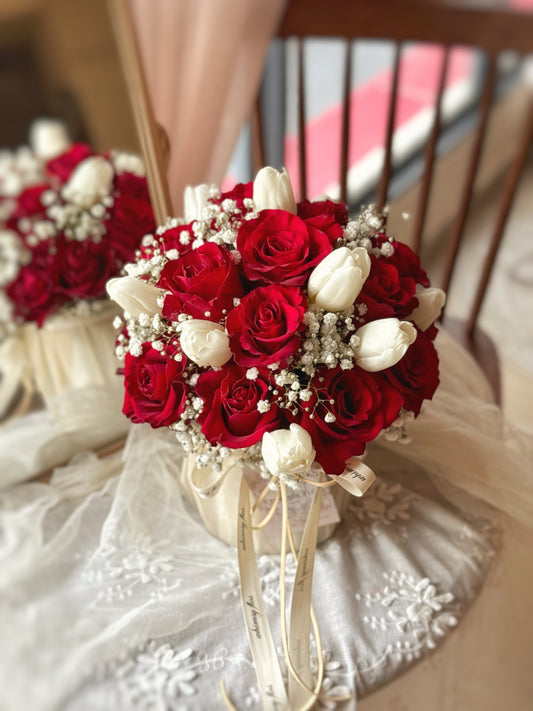  Fresh flowers bloom box placed neatly on a table, viewed from the side, highlighting its dome silhouette and romantic red-and-white color story featuring red roses, white tulips and baby breath

圆形玫瑰抱抱桶花盒置于桌面，从侧面拍摄呈现圆润花型与红白色系的浪漫玫瑰郁金香和满天星的搭配，散发典雅气质。