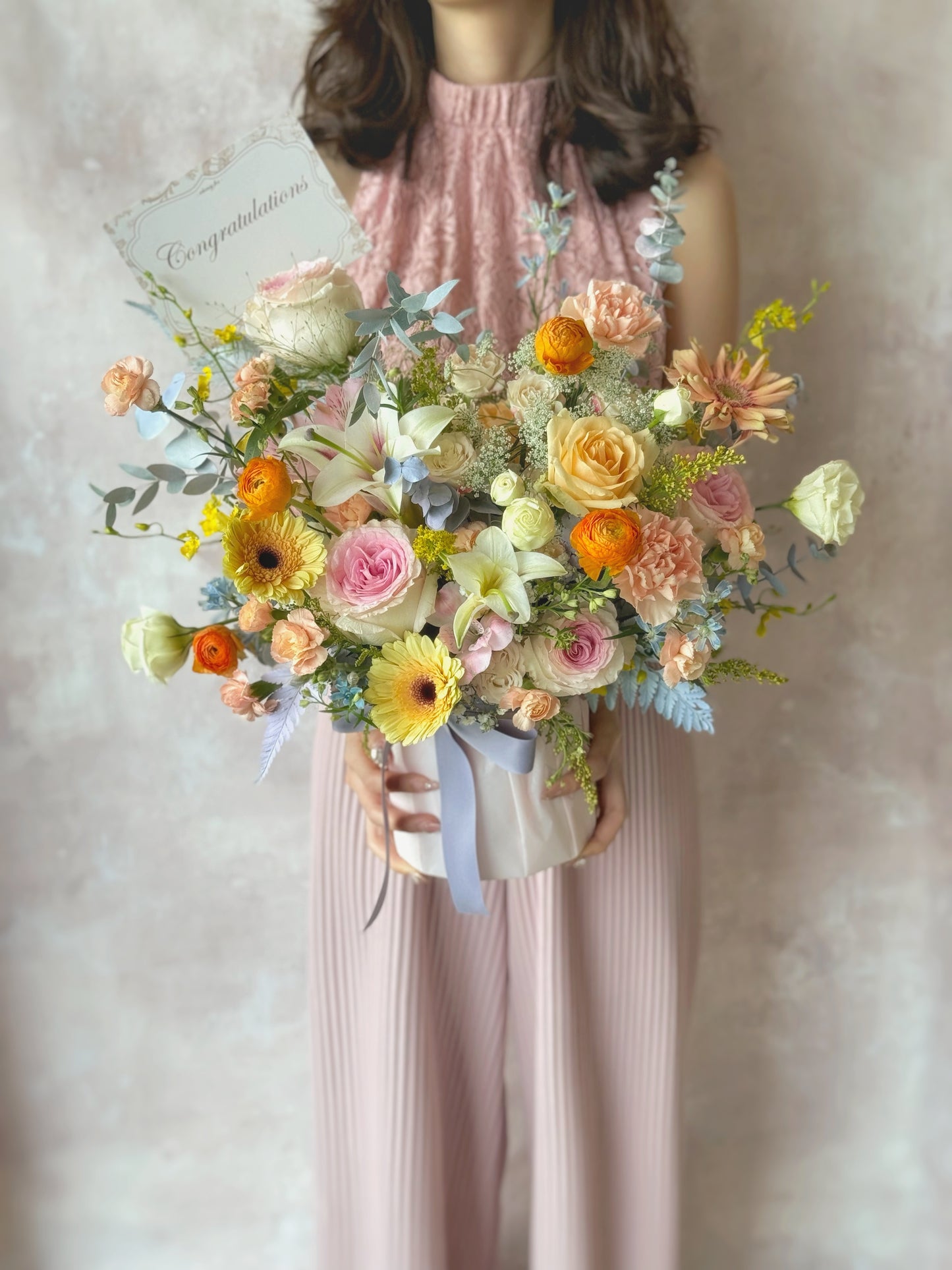 Candy pastel color theme fresh flowers bloom box holding by a model, in front view