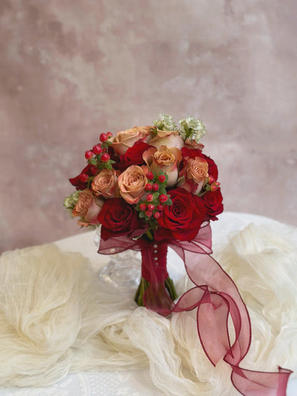 Round shaped fresh flowers bridal bouquet in nude pink and maroon color theme, featuring cappuccino roses, red Kenyan roses and other fillers. A perfectly symmetrical round bouquet featuring cappuccino roses and soft-toned florals, designed for a traditional Chinese wedding.
一款完美对称的圆形捧花，融合卡布奇诺玫瑰与柔和色调花卉，专为中式婚礼设计。