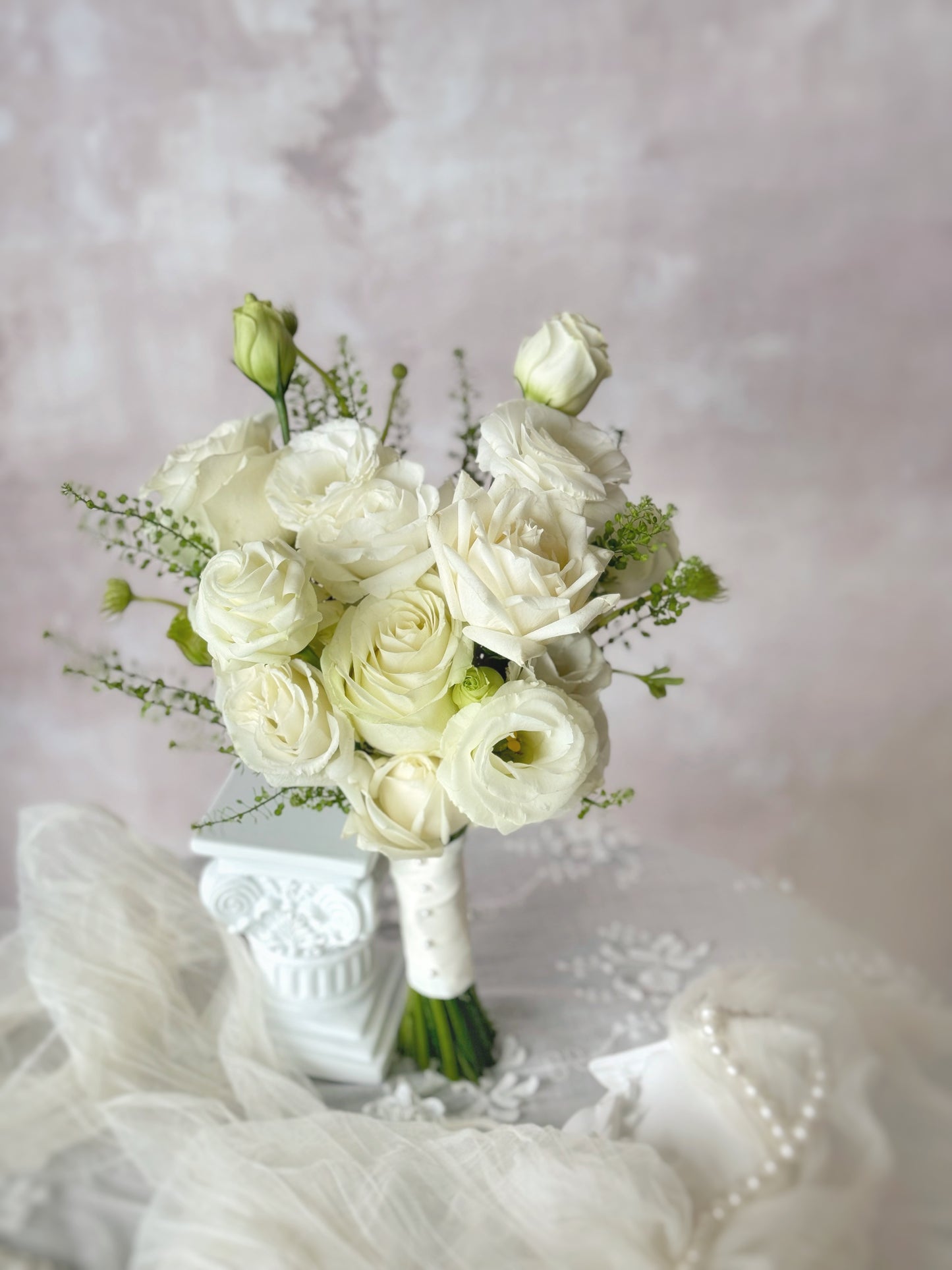 Minimalist white bridal bouquet resting on a table, showcasing the delicate beauty of fresh roses and eustoma flowers.
简约优雅的韩式婚礼捧花，采用白色玫瑰与洋桔梗，散发纯净浪漫气息