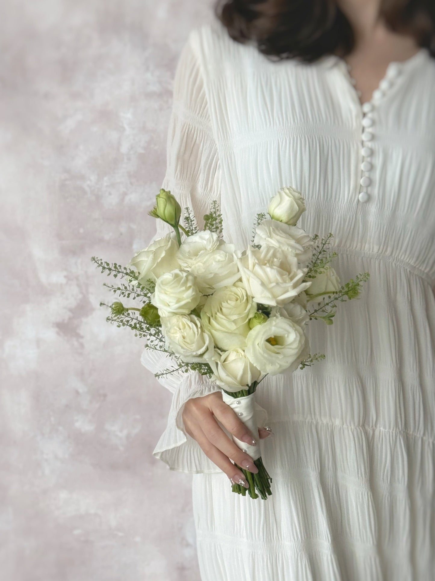 Model holding a classic Korean-style white bridal bouquet, featuring fresh roses and eustoma flowers for a soft and romantic touch
新娘手持经典韩式纯白捧花，增添优雅永恒的气质
