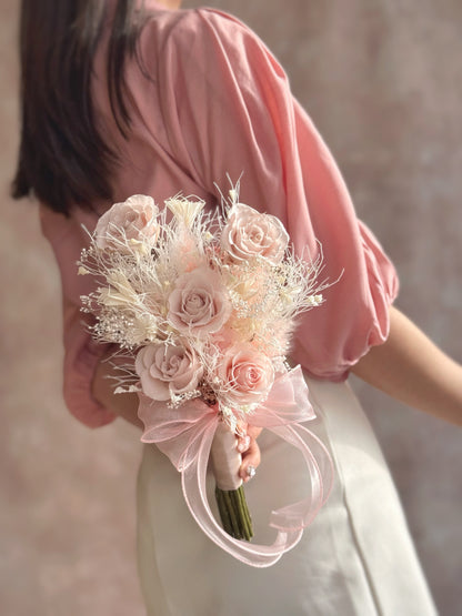 Chloe bouquet held by hand, featuring sweet preserved pink roses, soft hydrangeas, and dainty fillers, perfect for intimate ROM ceremonies.
“Chloe”花束手持展示，展现甜美的粉色永生玫瑰、柔和的绣球花和精致的填充花，完美适合亲密的登记结婚仪式。