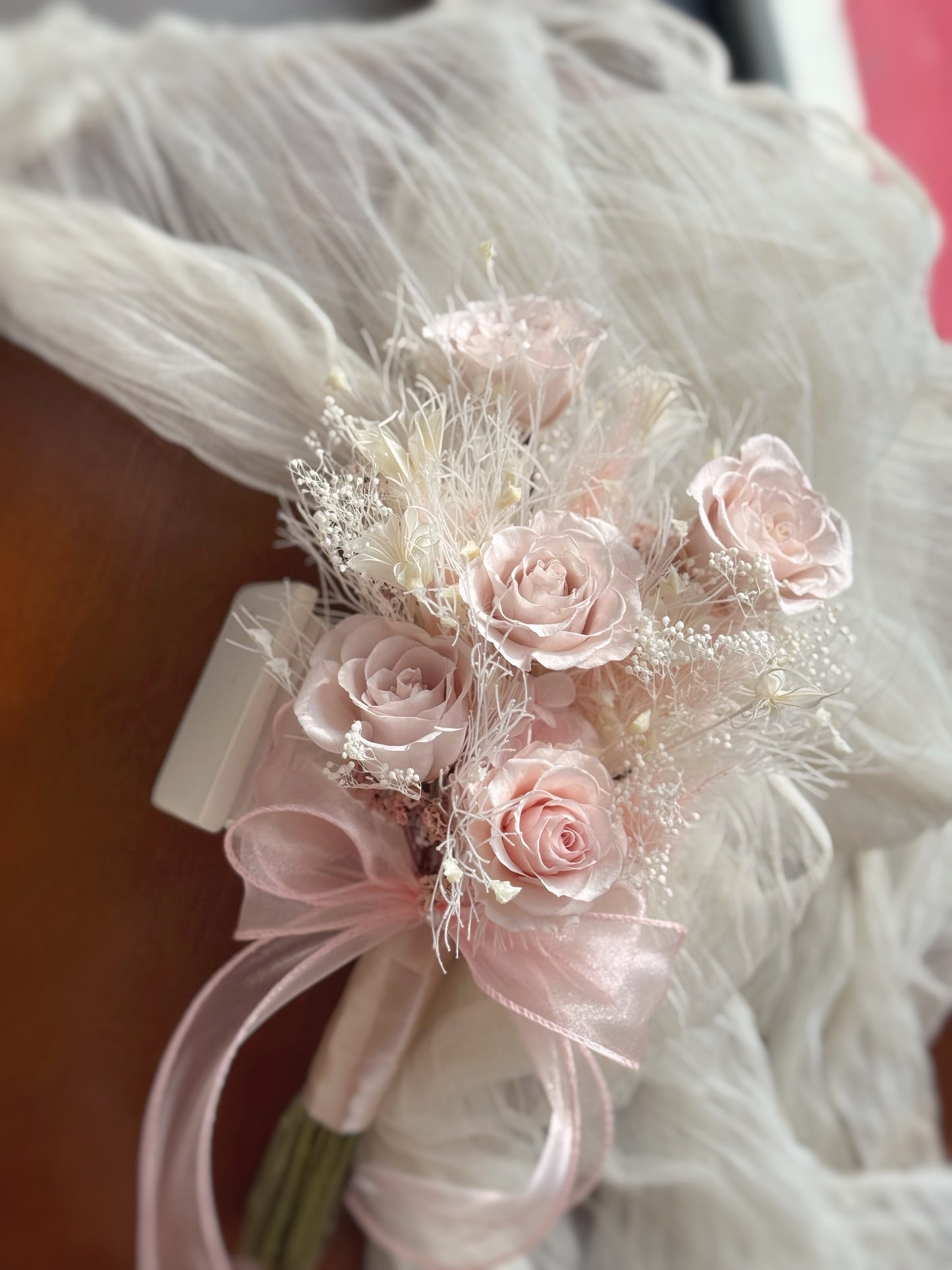 the Chloe bouquet displayed on a table, offering a full view of its delicate pink roses and soft hydrangeas, perfect for a sweet ROM bouquet.
“Chloe”花束放置在桌上，展示其细腻的粉色永生玫瑰和柔软的绣球花，完美适合作为甜美的登记结婚花束。