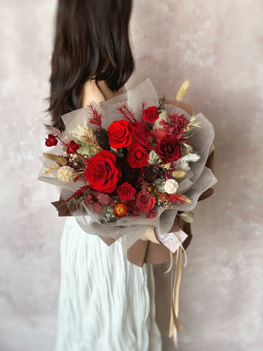 A model holding the Crimson Dusk bouquet, beautifully showcasing the deep, dramatic tones of red and maroon, adding a bold touch of elegance.
模特手持“Crimson Dusk”花束，完美展现了深红与酒红色的戏剧性色调，增添了一份大胆而优雅的氛围。