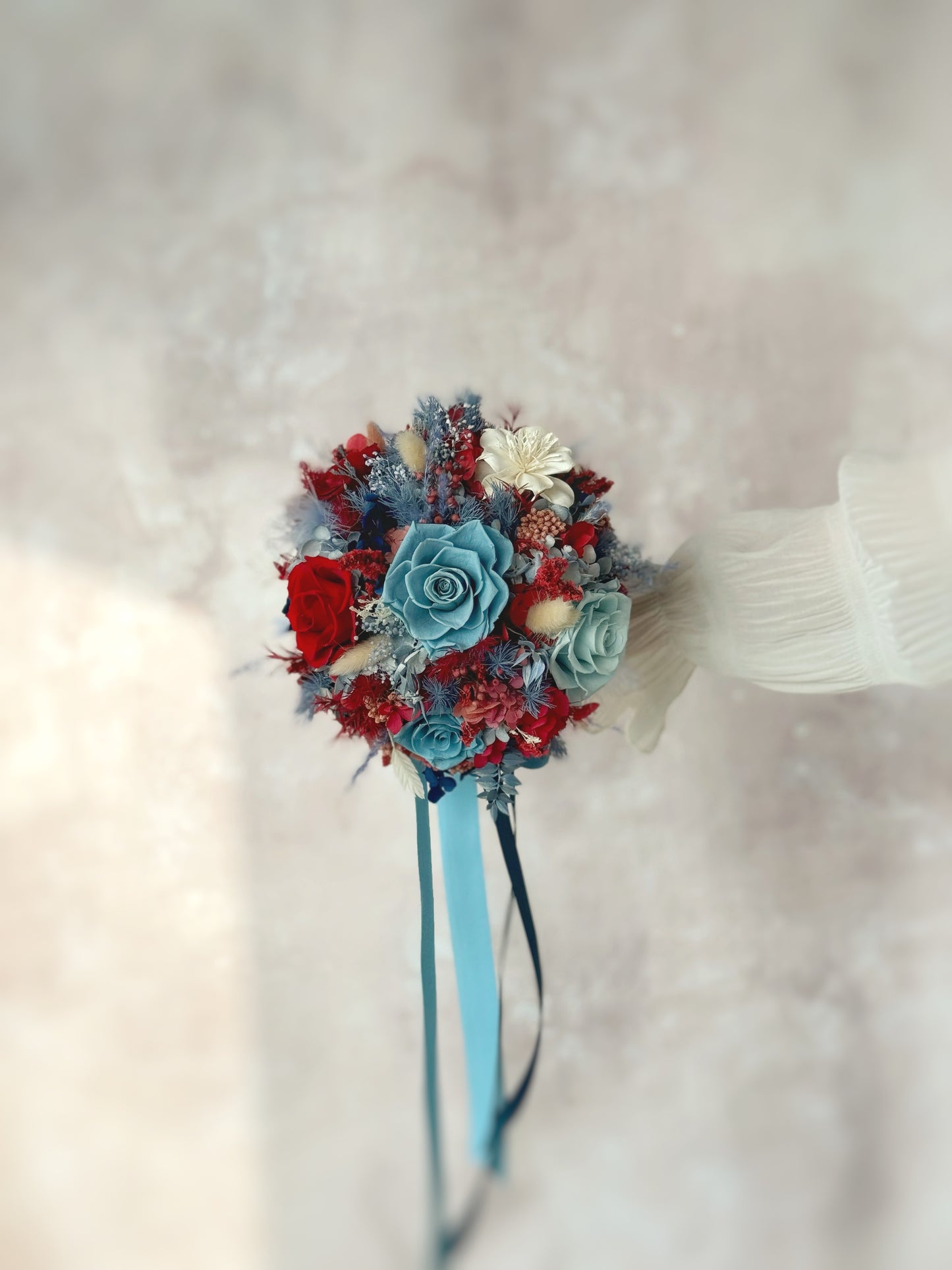 Crimson sapphire preserved flowers round shaped bridal bouquet front. The contrast between the deep crimson and soft blue flowers creates an eye-catching yet harmonious aesthetic.
深红色与柔和蓝色花材形成醒目但和谐的视觉美感。