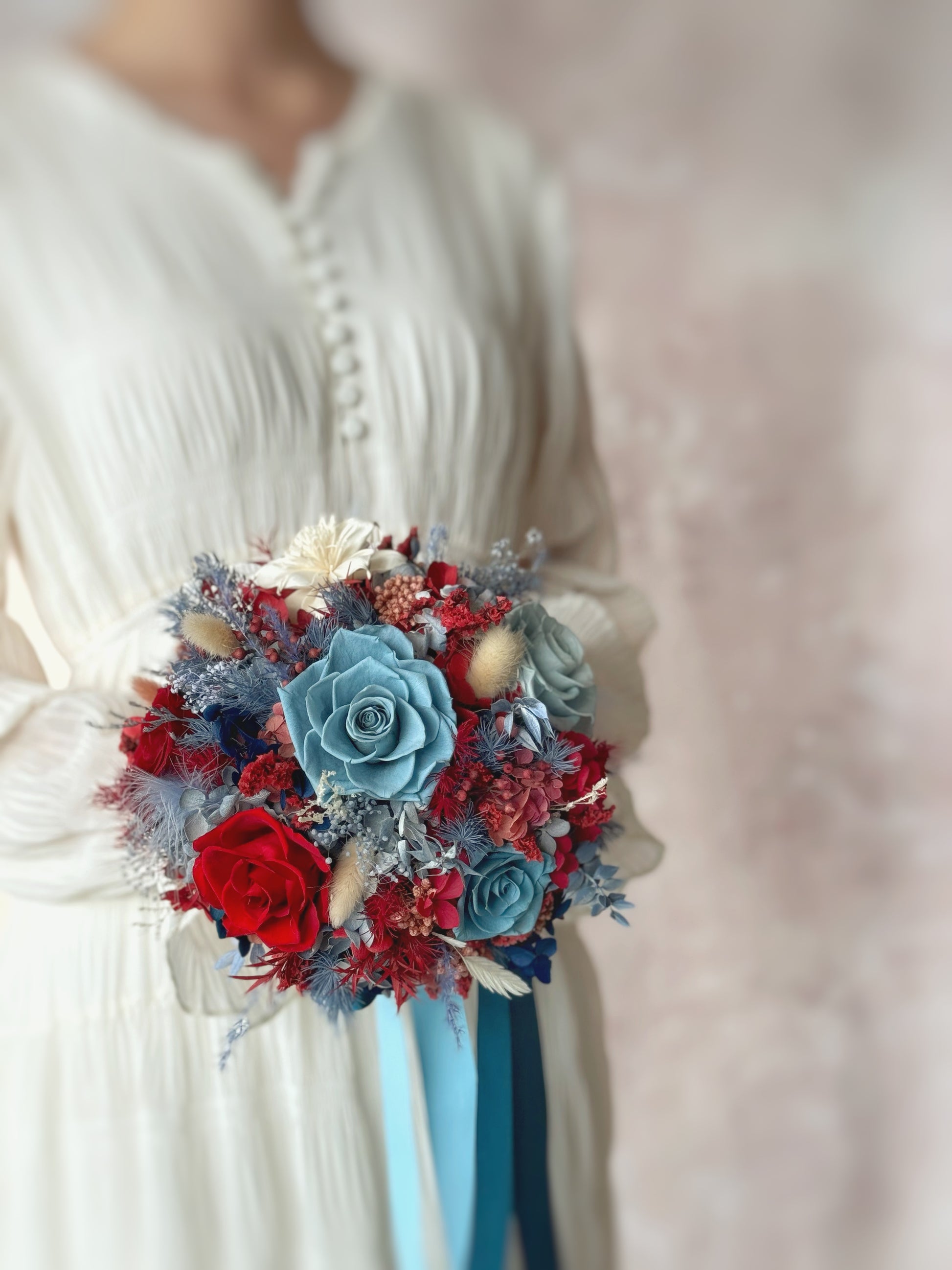 A model holding the bouquet, the rich color palette standing out beautifully against a white dress.
模特手持捧花，深红与蓝色的搭配在白色婚纱的映衬下更显典雅。