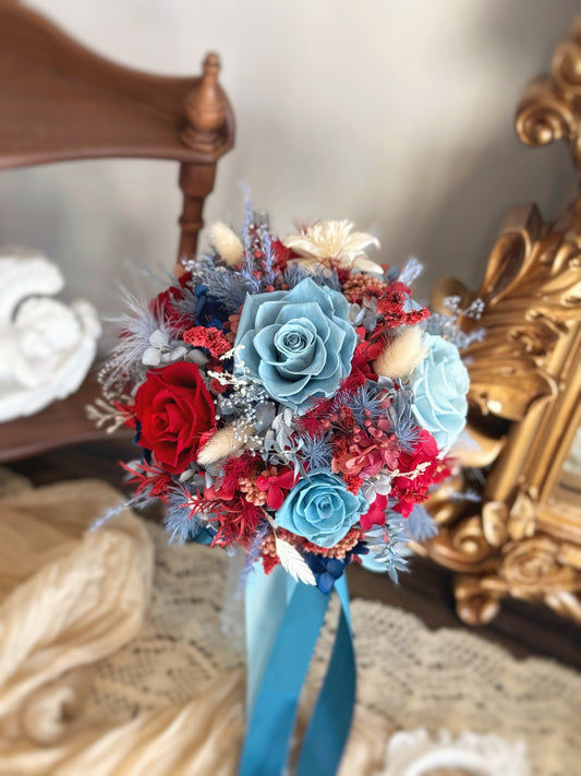 A preserved floral bouquet featuring a striking combination of crimson red and serene blue hues, elegantly arranged in a round shape.
永生花捧花，深红色与宁静蓝色完美结合，圆形设计展现典雅气质。