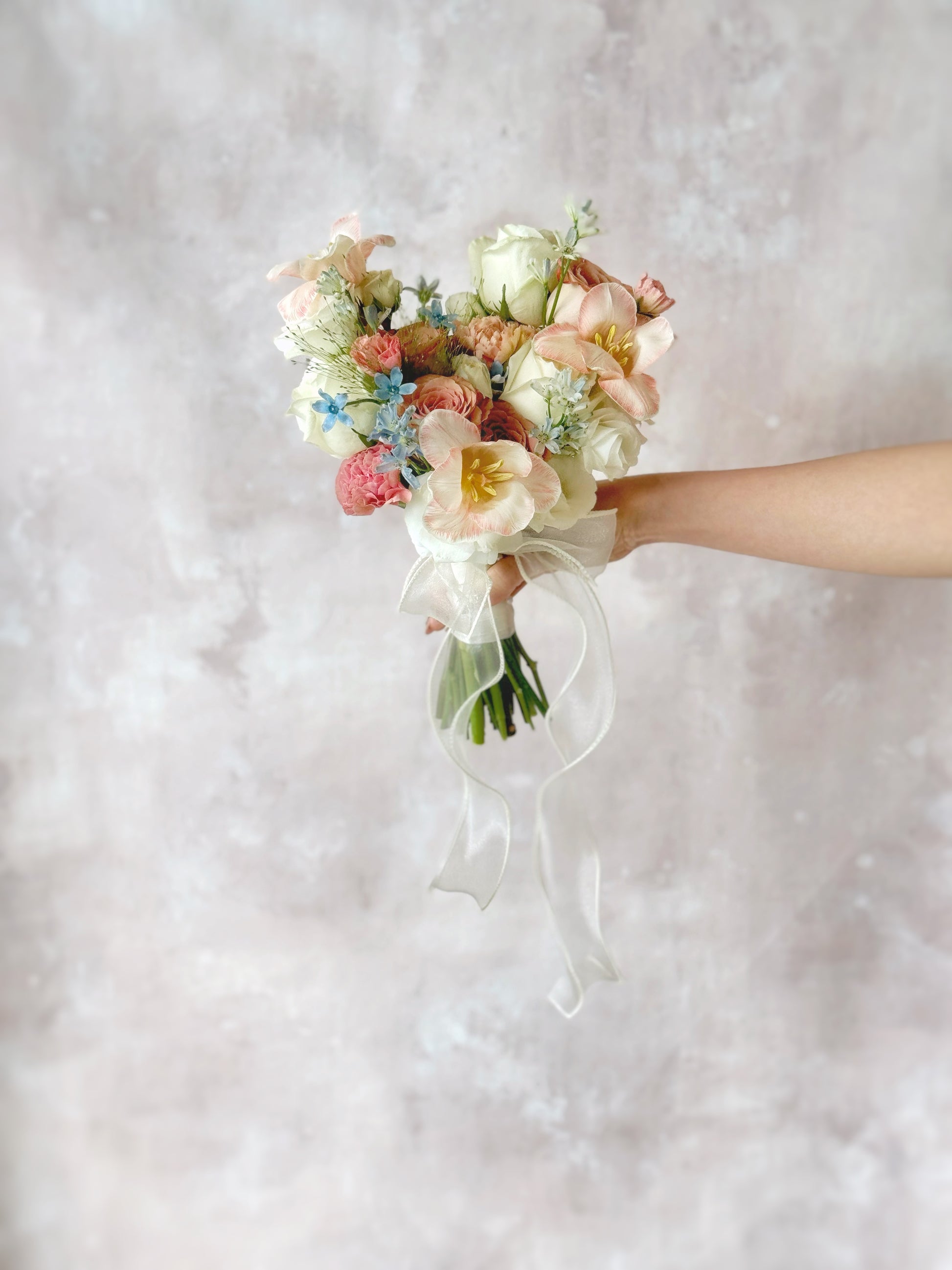 The exquisite mix of pastel pink, peach, and blue blooms, adding a dreamy and artistic touch to the bouquet
精致的粉色、蜜桃色与蓝色鲜花搭配，为捧花增添梦幻与艺术气息

