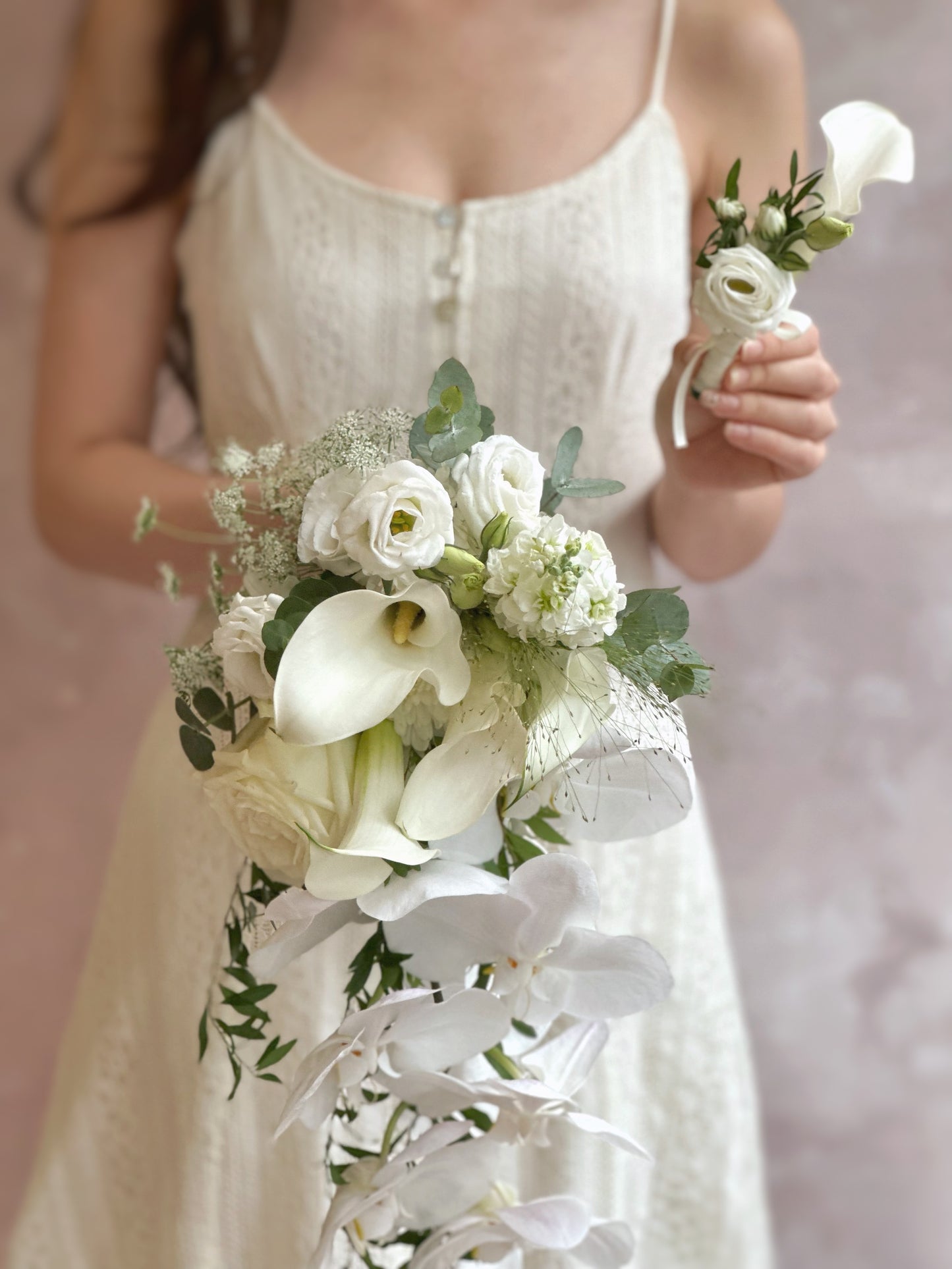 Bridal bouquet with cascading phalaenopsis orchids and matching groom's calla lily boutonniere for a perfect wedding duo
新娘捧花与新郎白色马蹄莲胸花搭配，蝴蝶兰垂坠设计，婚礼完美组合