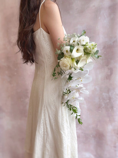 Delicate white phalaenopsis orchids and calla lilies arranged in a modern teardrop bouquet
现代水滴形捧花，搭配精致的白色蝴蝶兰与马蹄莲