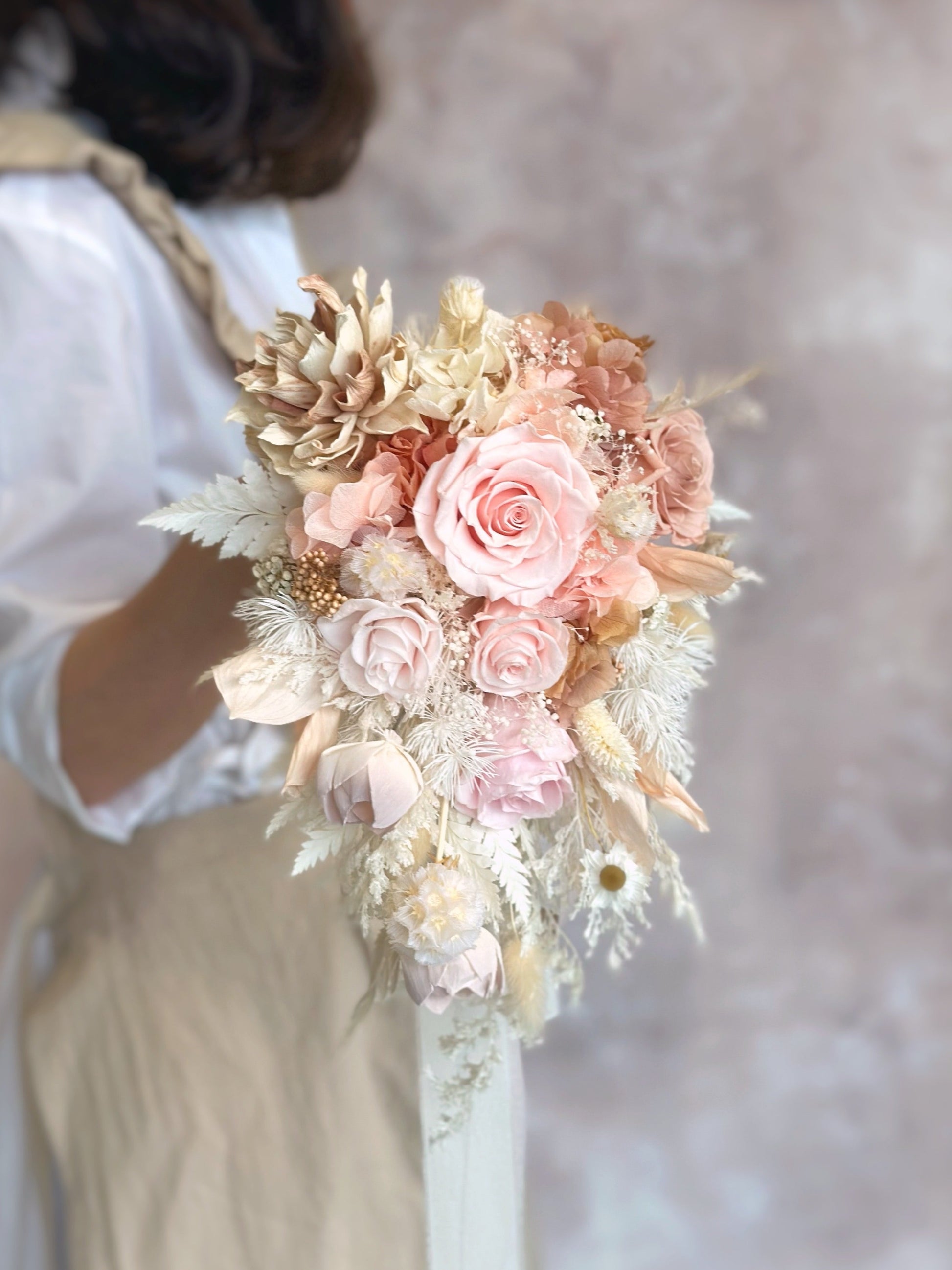 A bride holding the cascading bouquet, its elegant ombré tones complementing a mermaid-style wedding gown.
新娘手持瀑布形捧花，优雅渐变色调完美搭配美人鱼婚纱。
