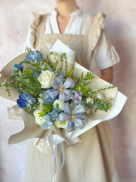 Front view of the Enchanted Twilight bouquet, featuring stem-dyed tulips in violet and deep blue tones, wrapped artistically with greenery.

正面展示 Enchanted Twilight 花束，融合紫色与深蓝色染色郁金香，搭配绿叶与艺术感包装。