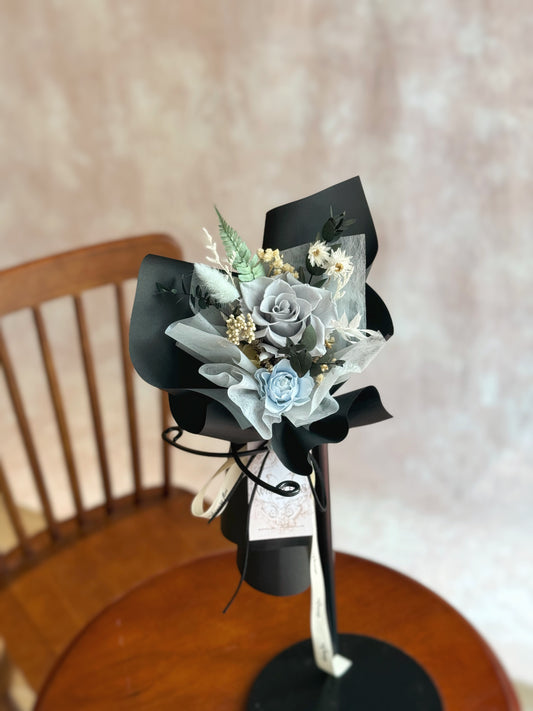 The Finn bouquet displayed on a table, providing a full view of the sleek and sophisticated arrangement with its dark tones and minimalistic style.
“Finn”花束放置在桌上，展示其简洁精致的排列，深色调与极简风格完美融合。