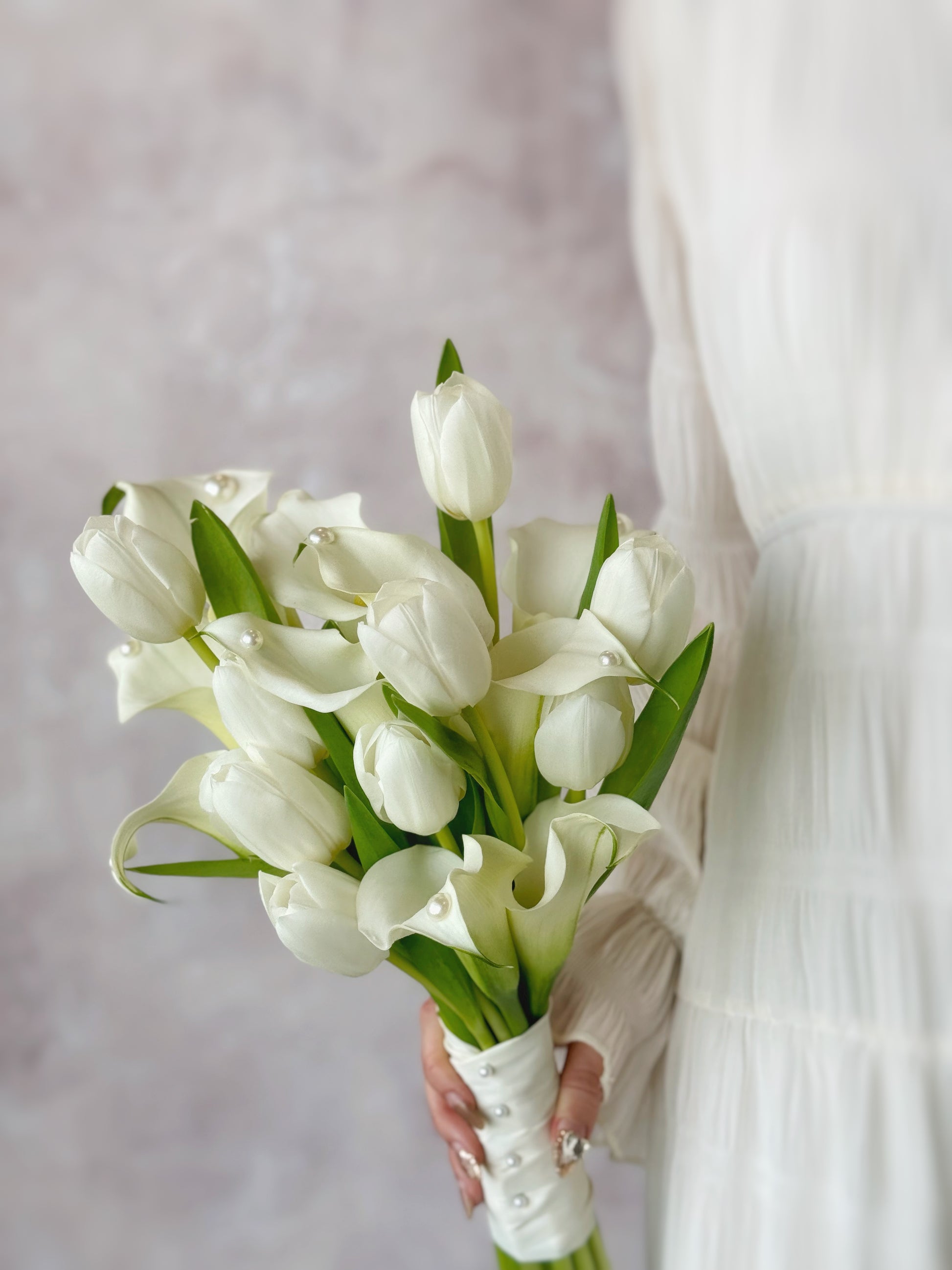 Genuine fresh flowers bridal bouquet calla lily holding the bouquet
新娘手持优雅排列的马蹄莲与郁金香捧花，打造精致现代新娘造型

