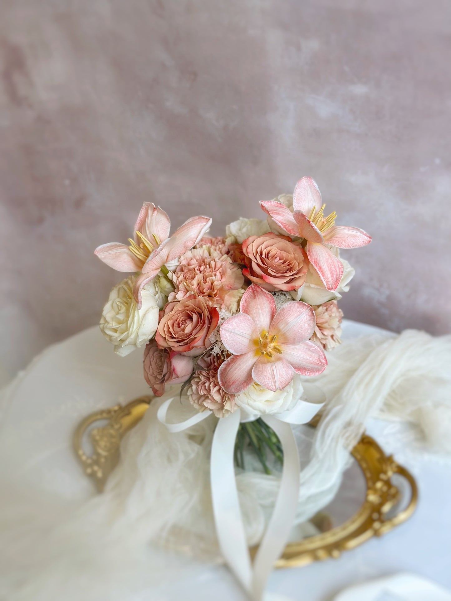 A delicate and romantic blush-toned bouquet resting on a soft fabric backdrop, highlighting the dreamy peachy apricot tulips as the centerpiece.
甜美裸粉色调捧花安放在柔软布料上，梦幻的蜜桃杏粉色郁金香成为亮点。

