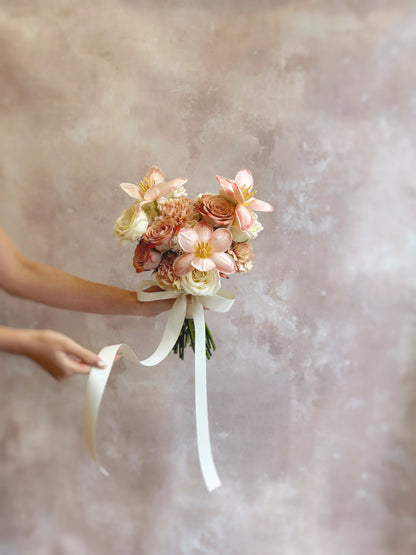 A close-up of the bouquet’s fully bloomed tulips, showing the soft ruffled petals in peachy apricot tones blending with pastel cream florals.
捧花特写，展示完全绽放的郁金香，蜜桃杏色花瓣柔软飘逸，与奶油色花朵和谐融合。

