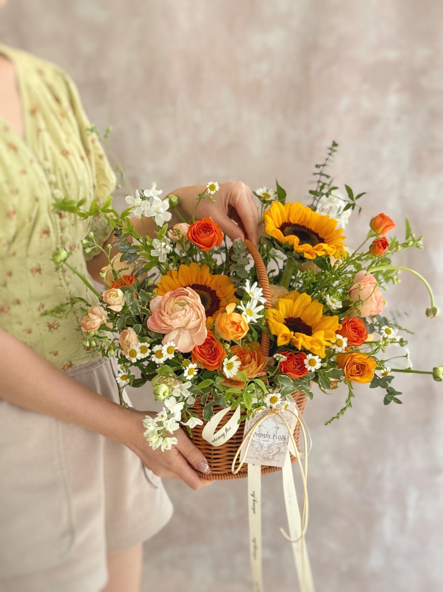 Side view showing the natural shape of the basket and the layered mix of golden florals and fresh greens.
 侧面视角呈现花篮自然轮廓，金黄色花材与绿叶层次分明、协调清新。