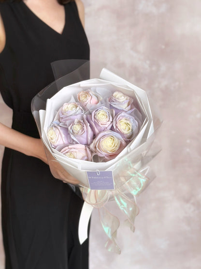 Elegant round bouquet featuring Aurora spray painted roses in white and transparent wrappers