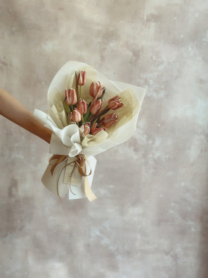 Holding a rustic brownie coloured stem dyed tulips bouquet